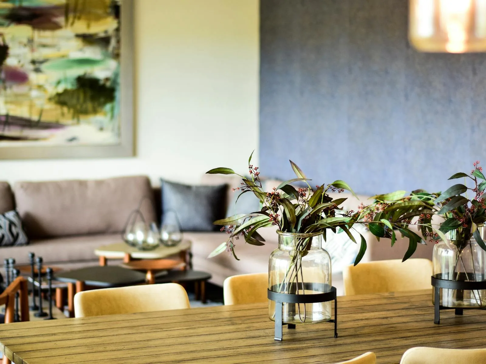 Dining and living area with glass vases, greenery, warm light, and muted abundance colors