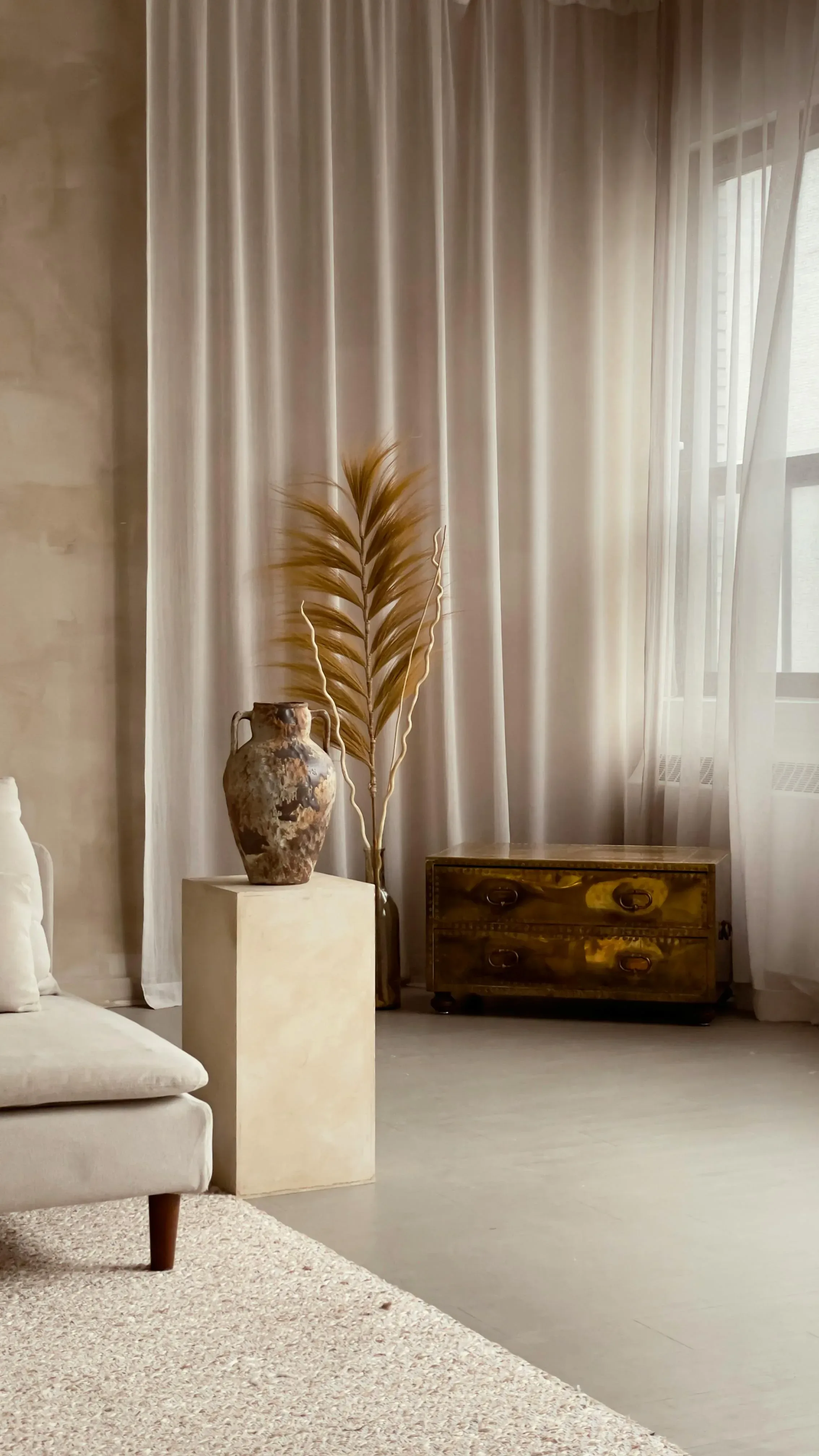 Vintage wood chest with pottery, dried stems, soft curtains, and warm natural light