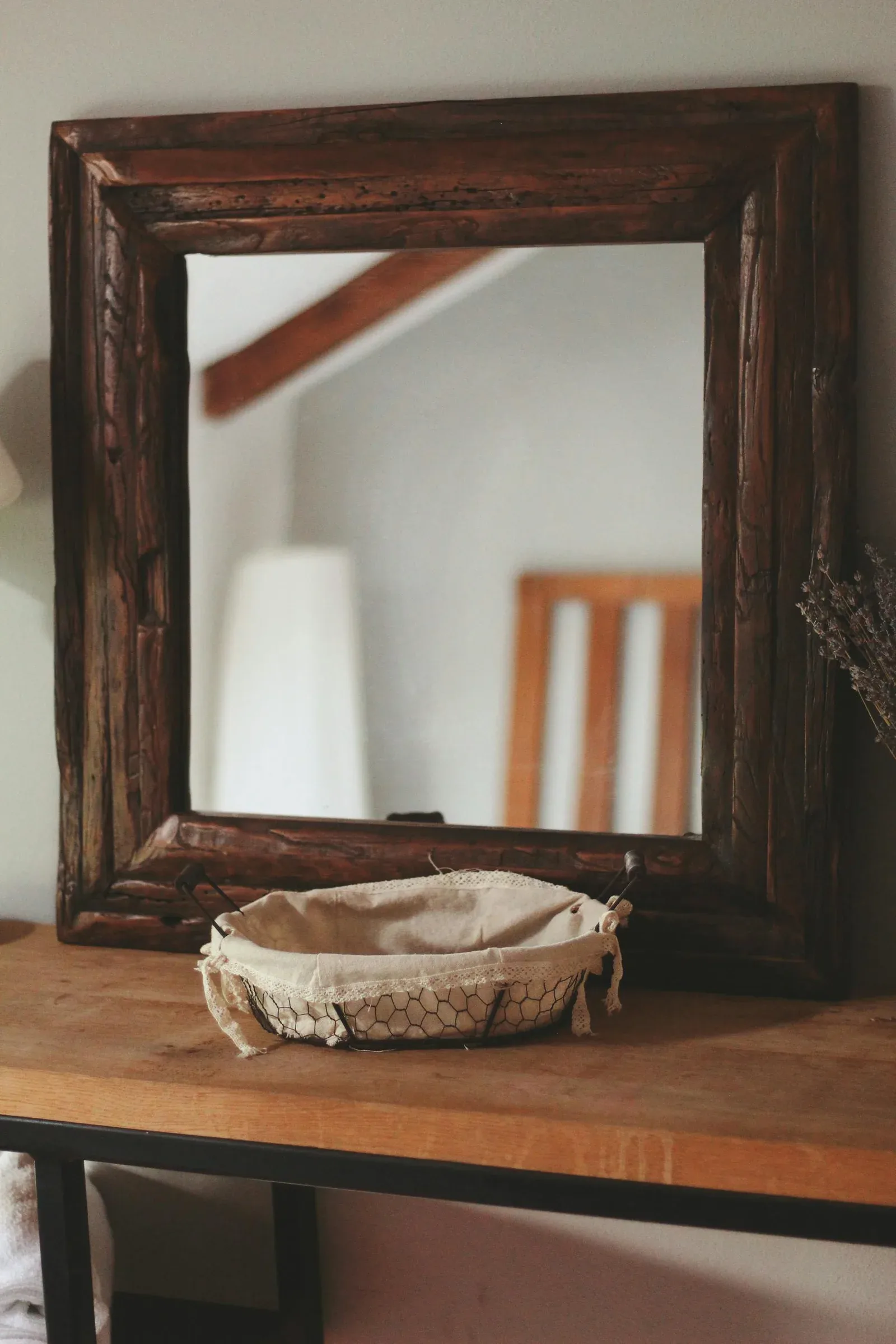 Warm wood console with mirror, small plant, lamp, and soft layered decor