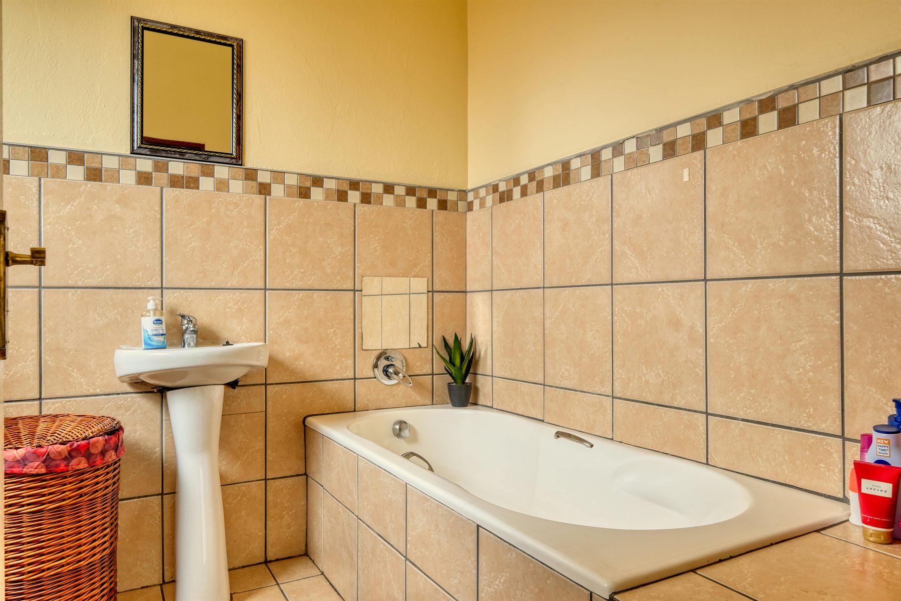 Bathroom with sandy tan tile, warm walls, and a tub with a simple natural palette