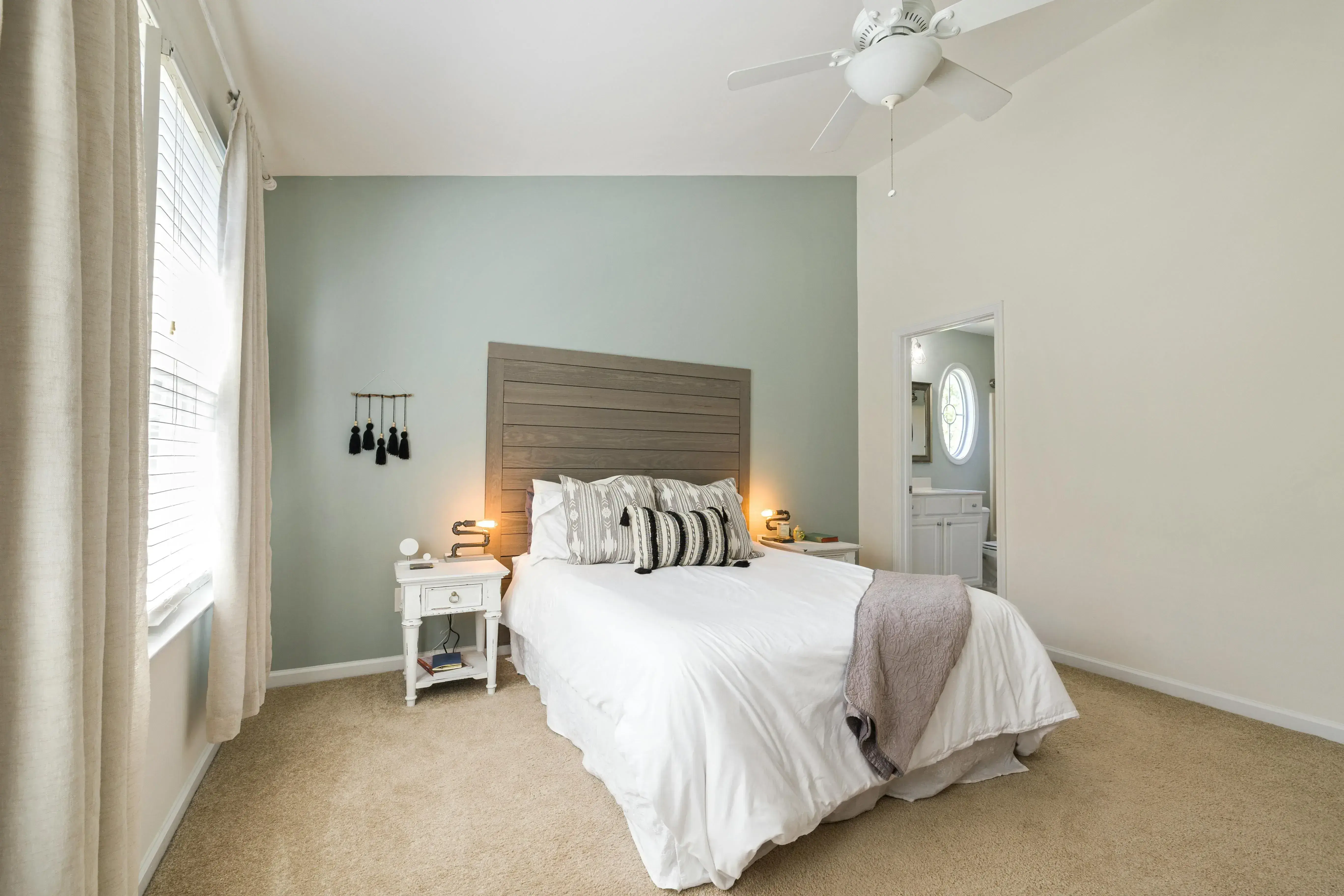 Neutral bedroom with the headboard on a solid wall, the doorway visible from bed, and one clear path at the side