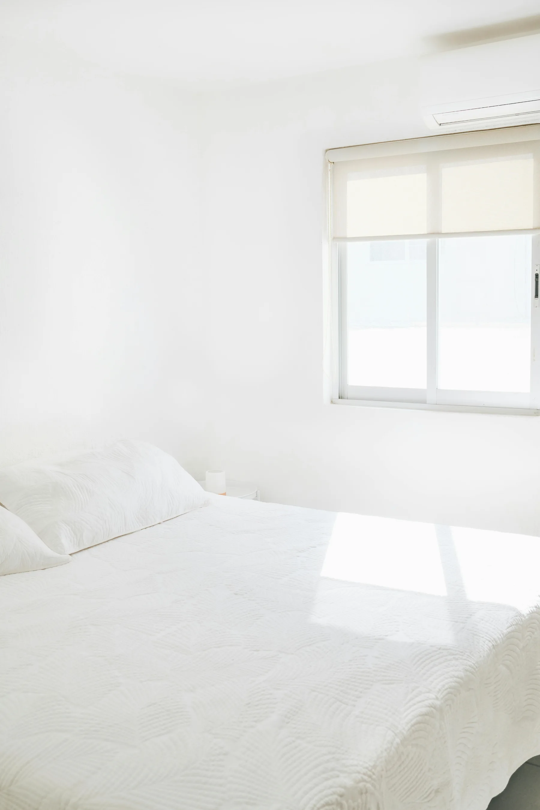 Soft white bedroom with a calm bed wall, edited decor, and a restful uncluttered feel