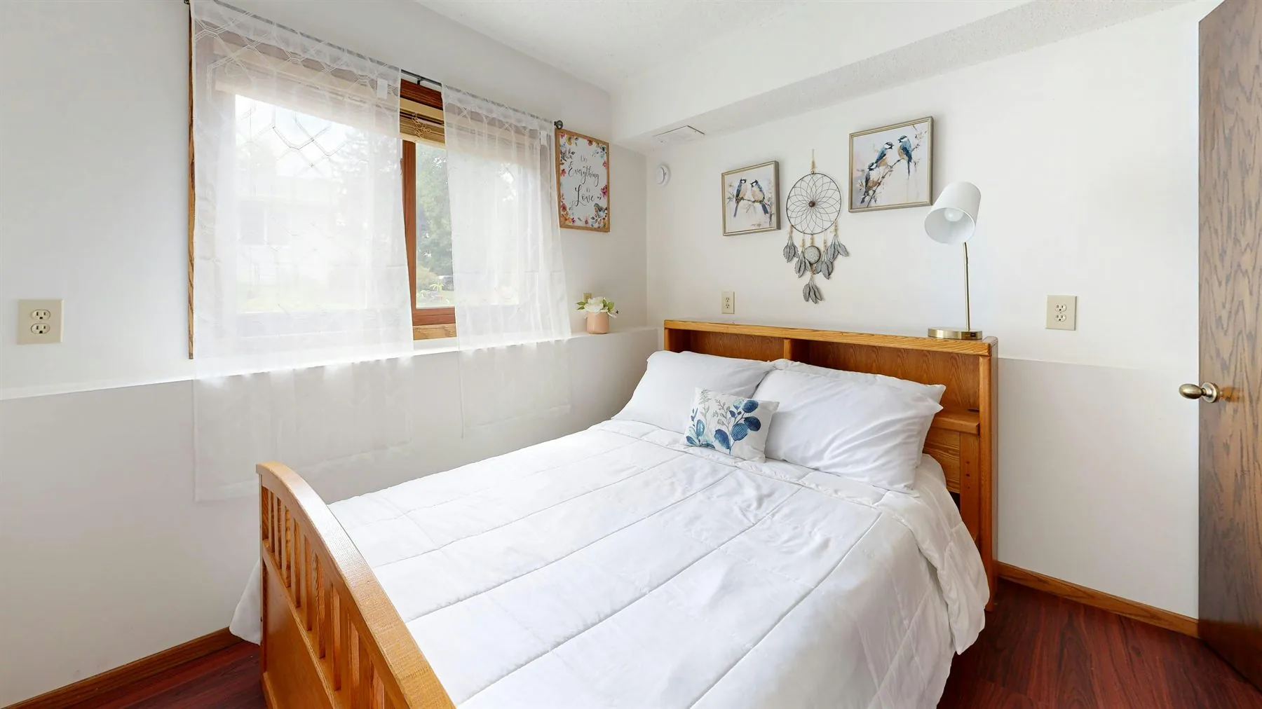 Soft bedroom detail with round table, flowers, pale bedding, and warm wall trim