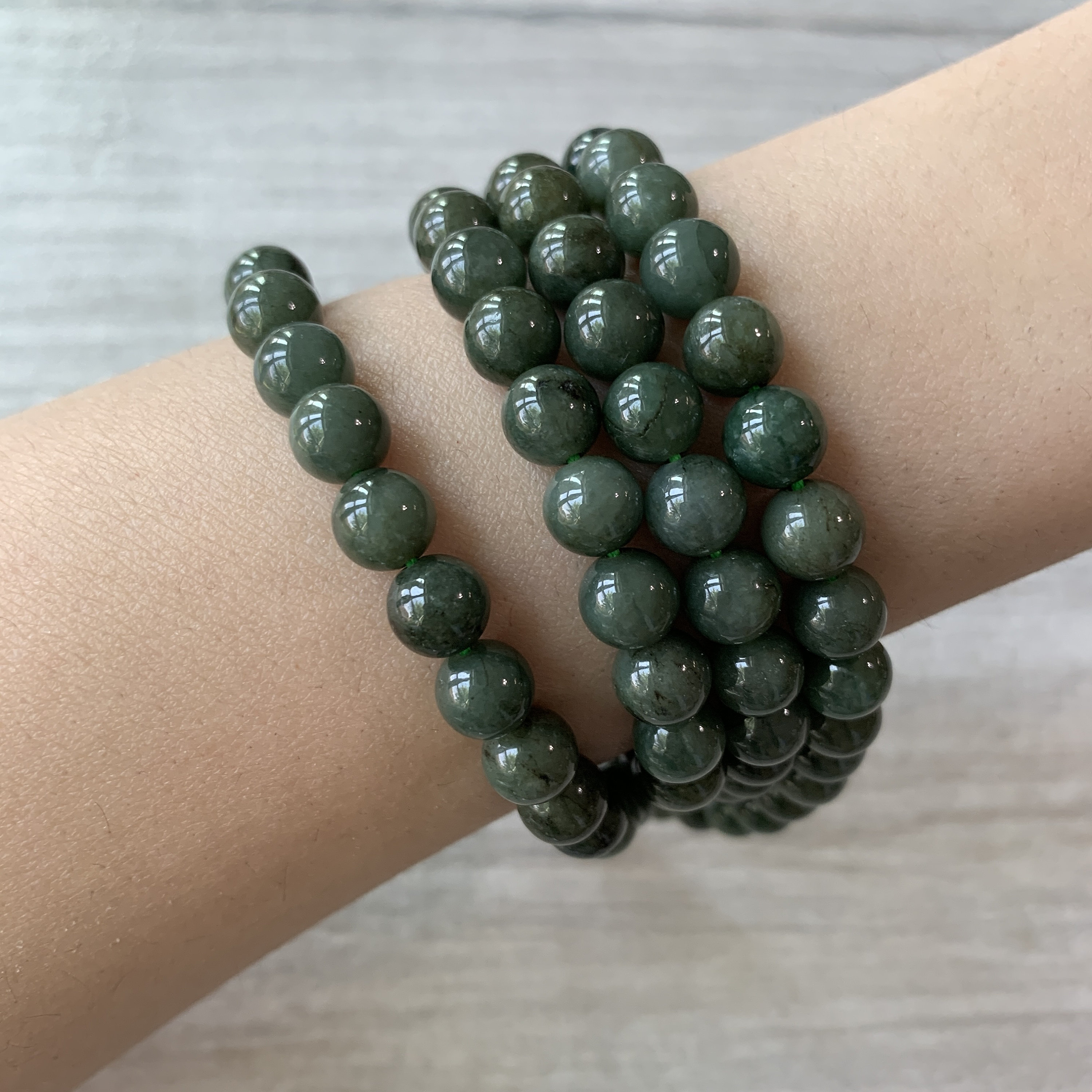 Dark green jade bead bracelets worn on the wrist showing a richer daily-wear bracelet direction
