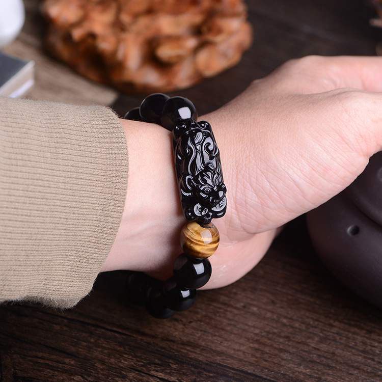 Jade and darker stone feng shui bracelet worn on the wrist with carved protective detail