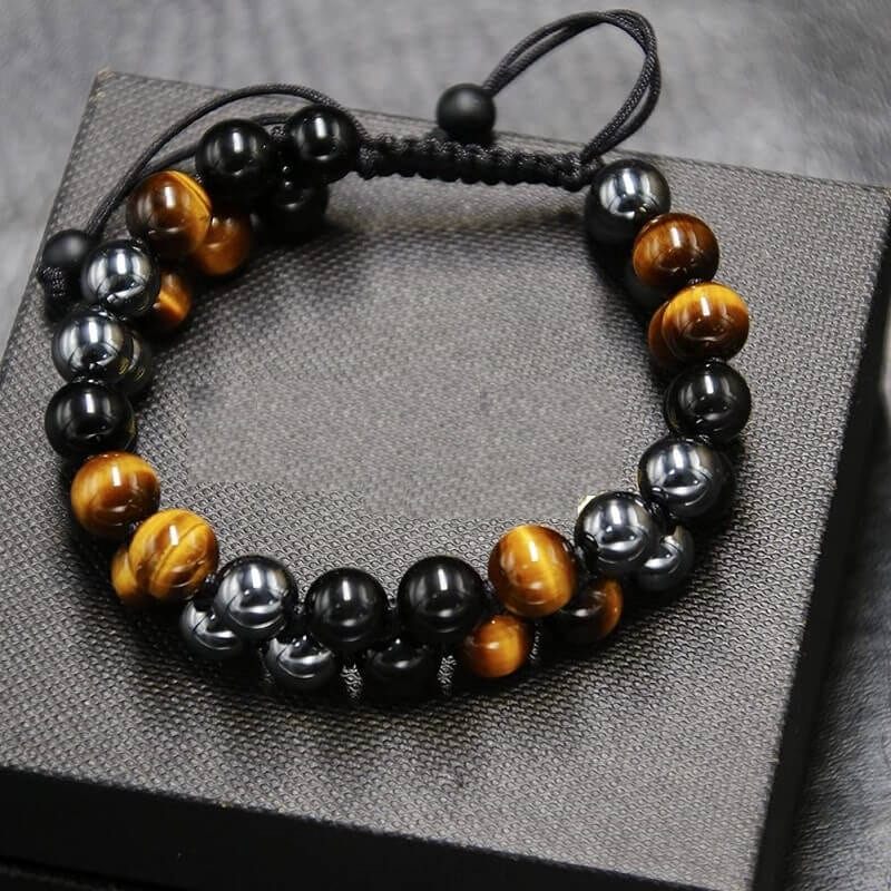 Black obsidian and tiger eye bead bracelet on a dark textured display block