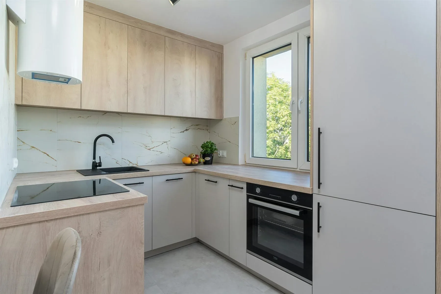 Kitchen with warm light wood cabinets, pale counters, and a clean soft palette