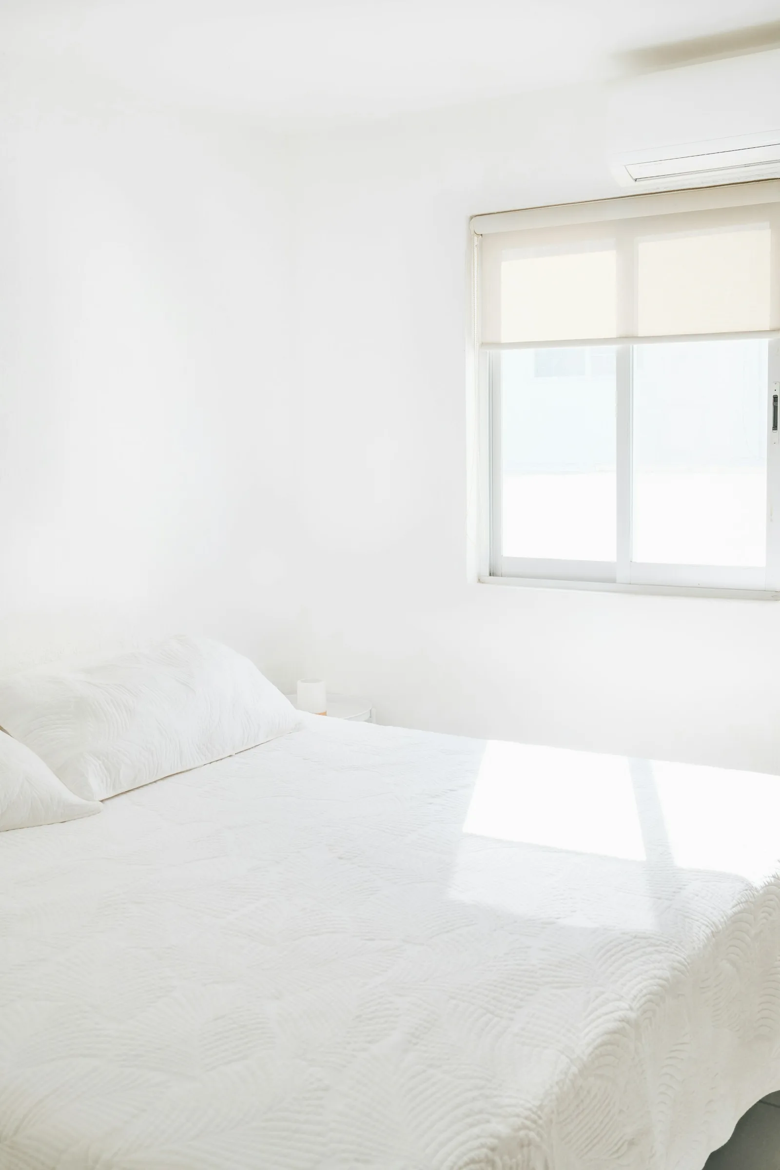 Very white bed and bedding in strong daylight with little warmth
