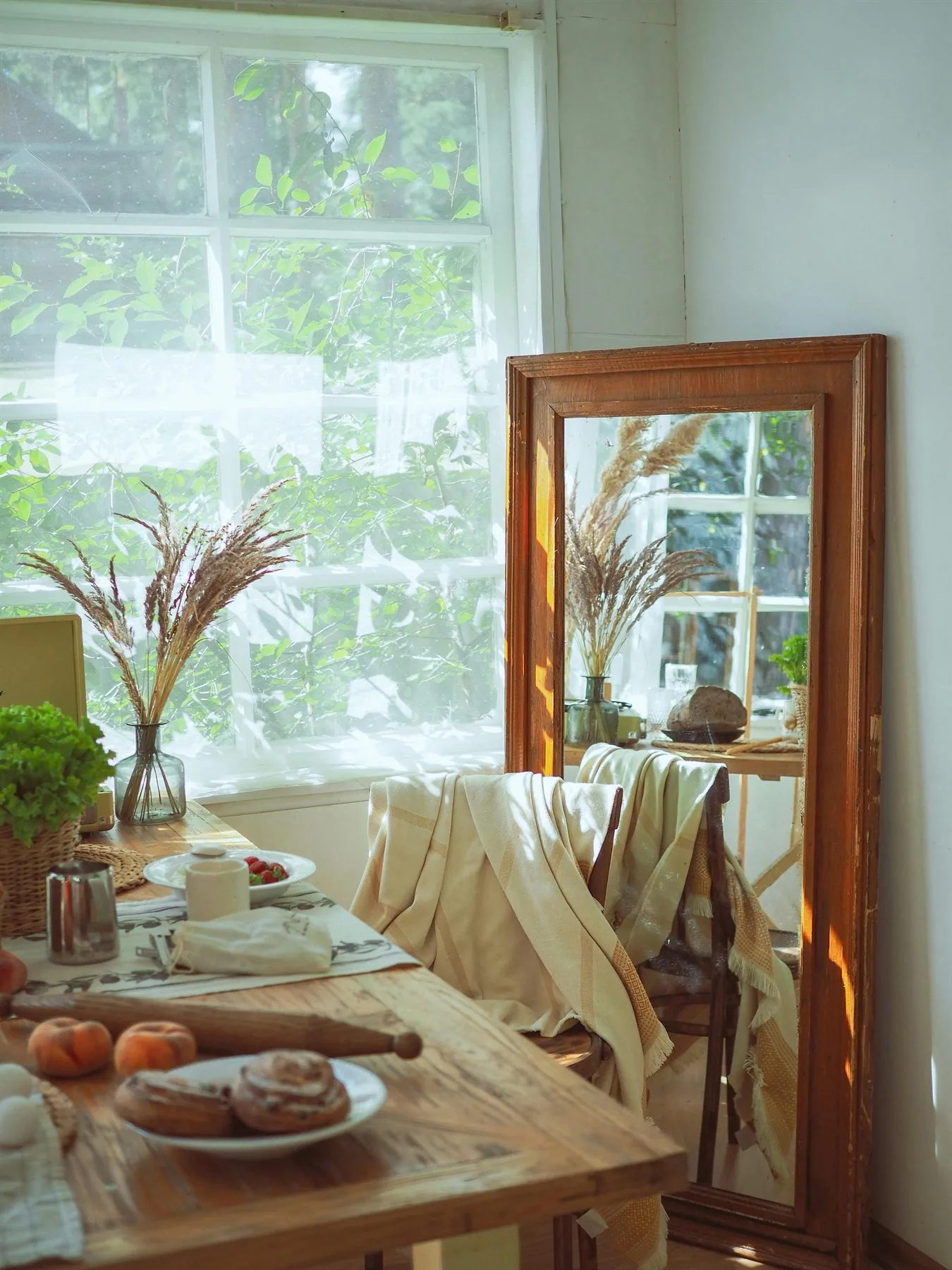 Dining table by a bright window with a floor mirror reflecting the table and light
