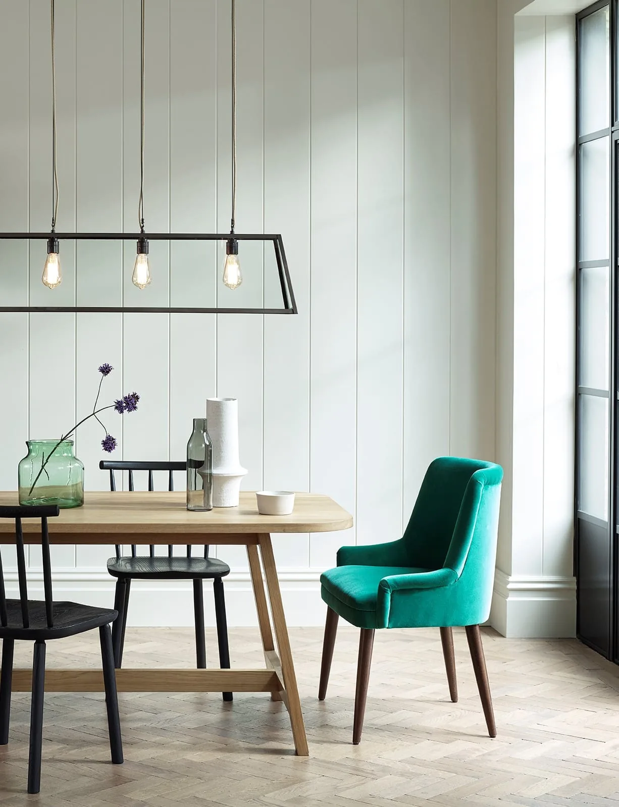 Light dining room with a wood table and one green accent chair