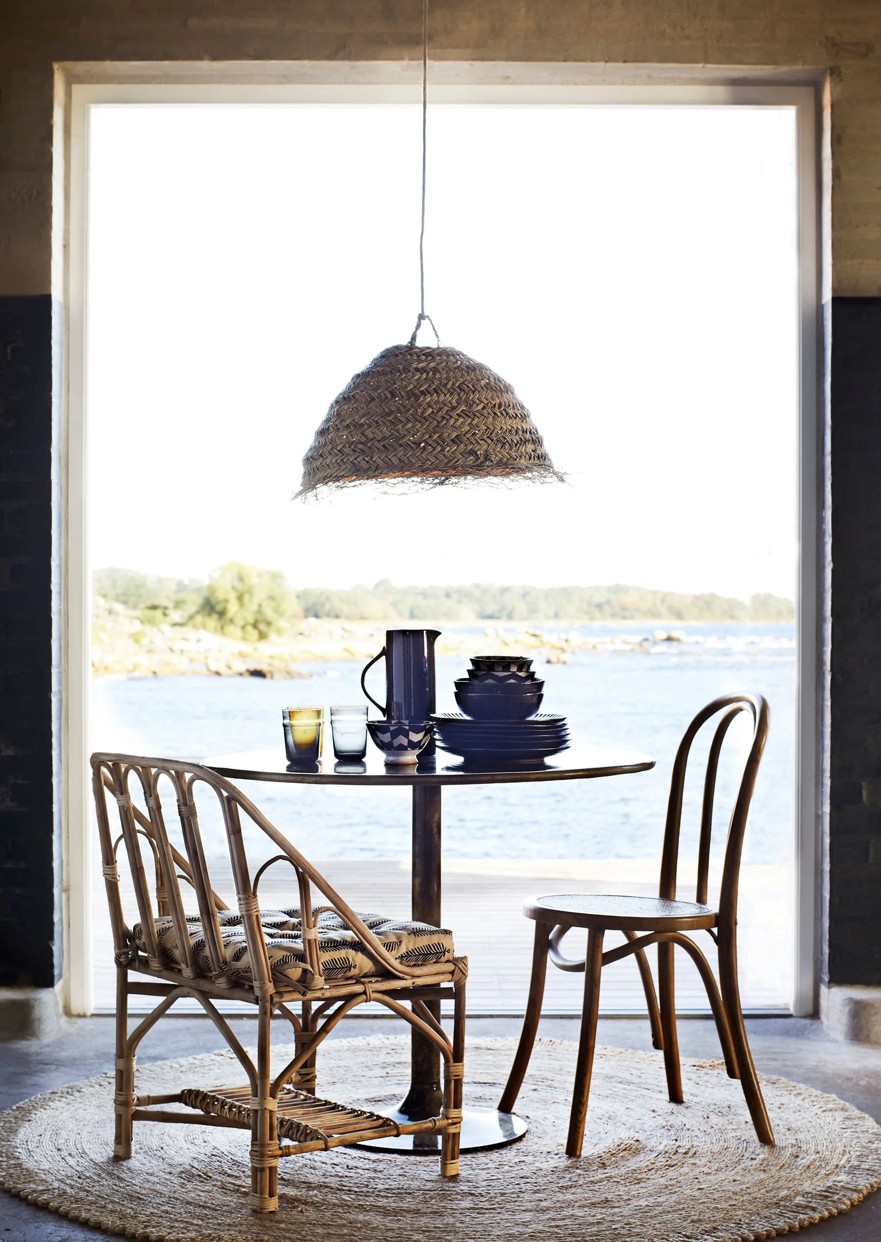Small dining table with a woven pendant and lighter wood finishes
