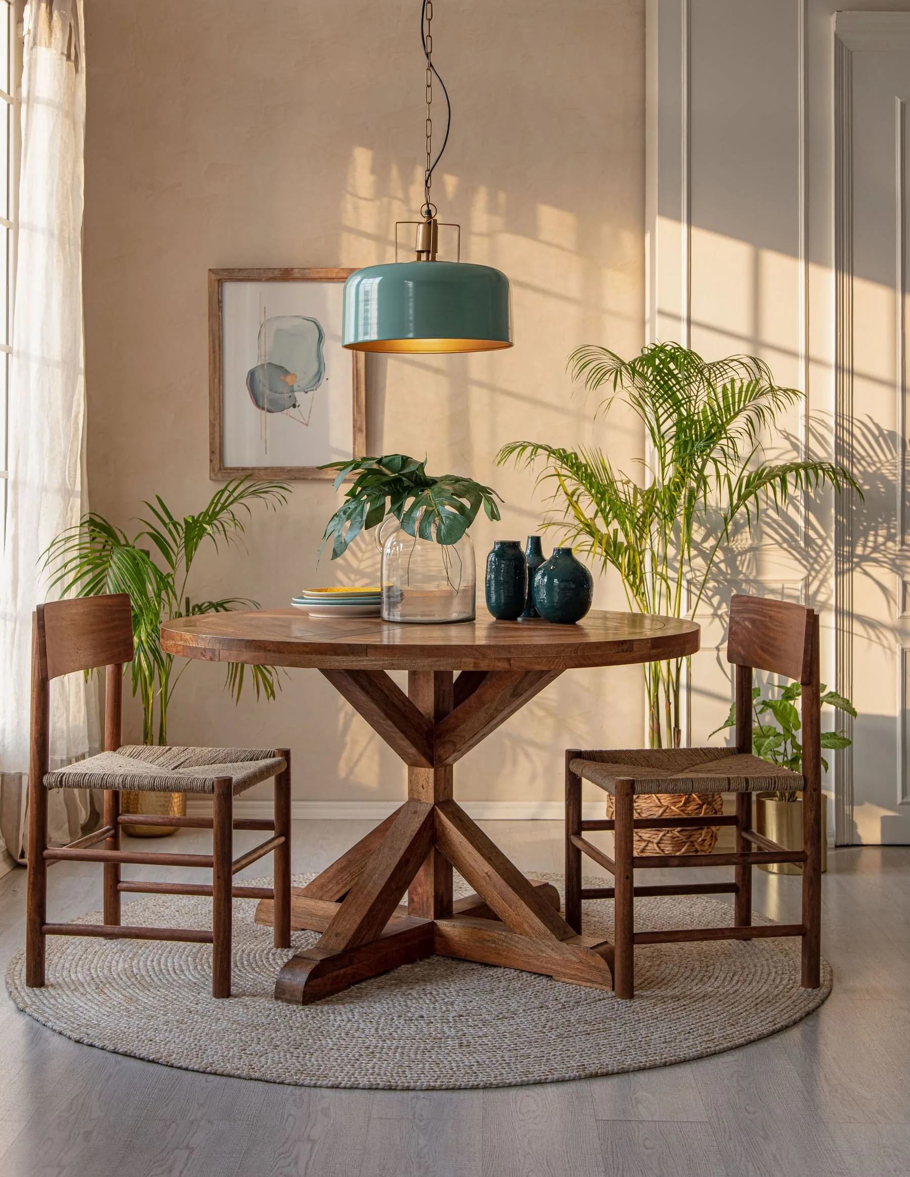 Small round wood dining table with a sage pendant and nearby plants