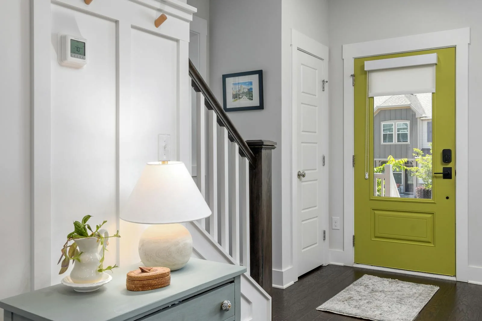 Bright entry with a lamp, small plant, open floor space, and a clear front door