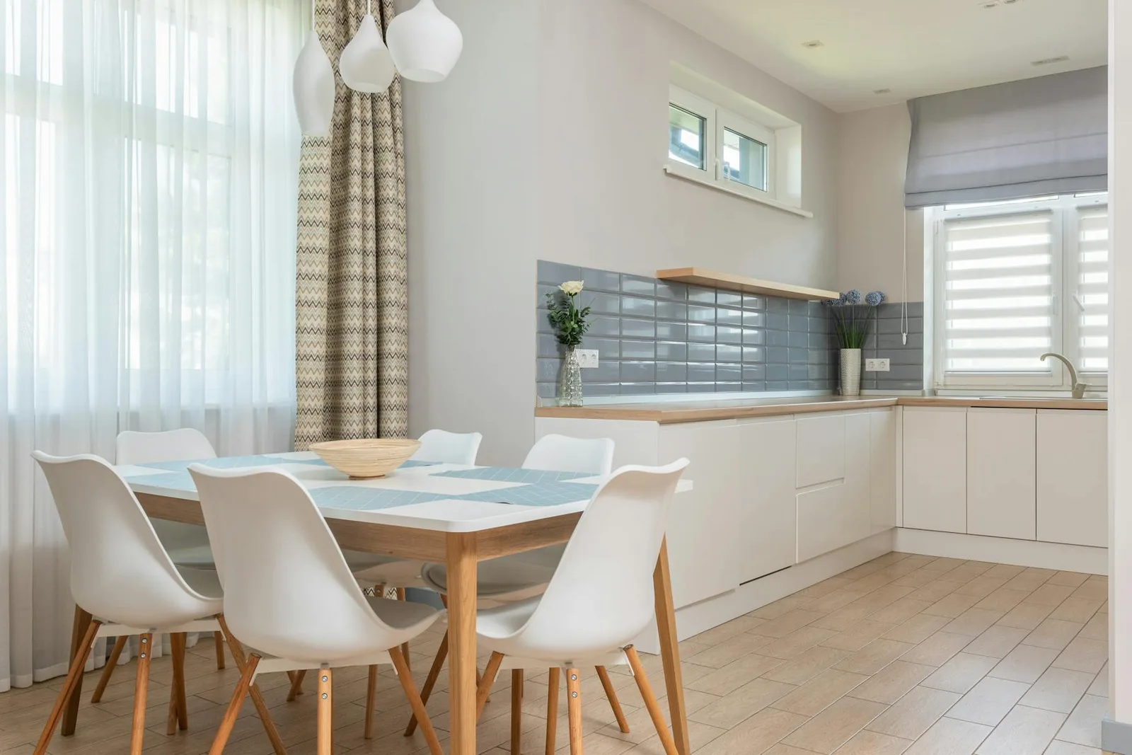 Bright dining area with beige curtains, light wood floor, and a soft neutral palette