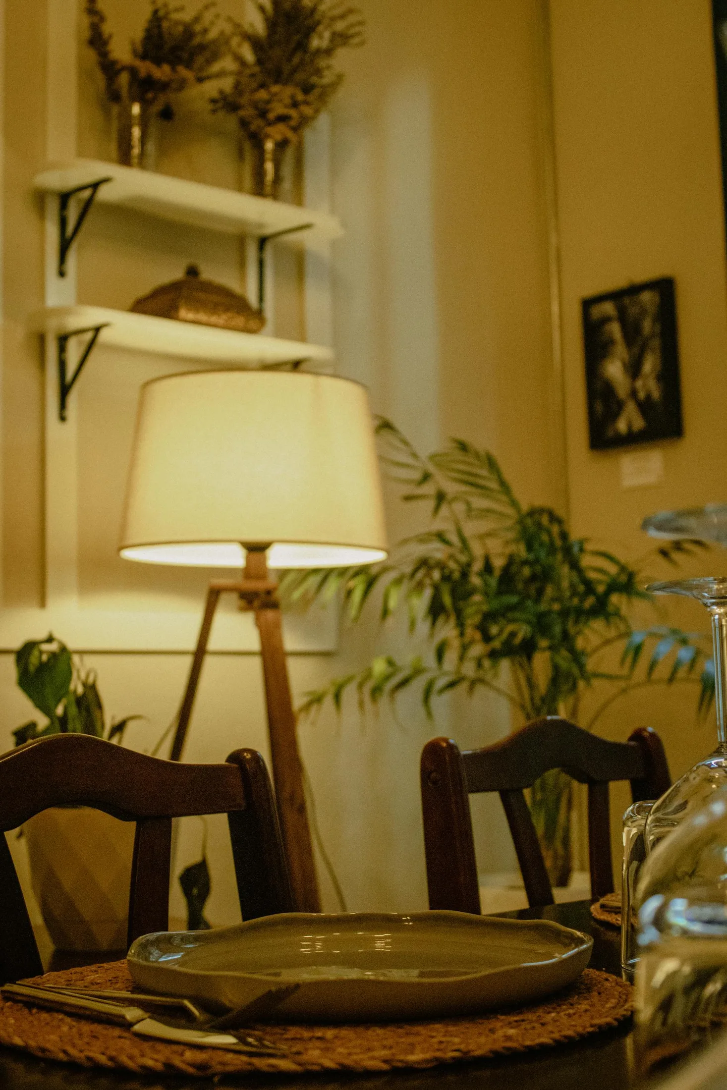 Warm dining room detail with lamp glow, plants, and natural materials