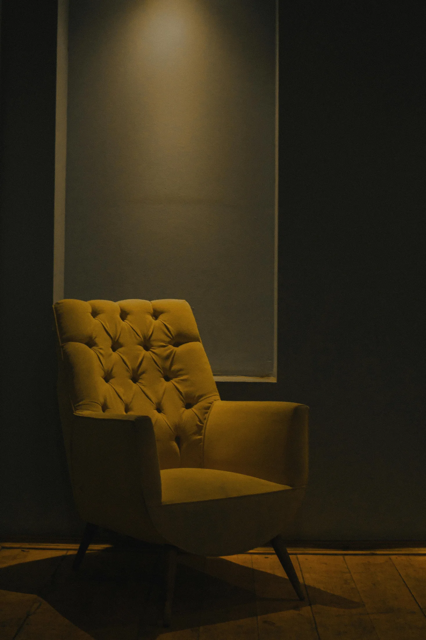 Amber yellow chair in a moody corner with warm directional light