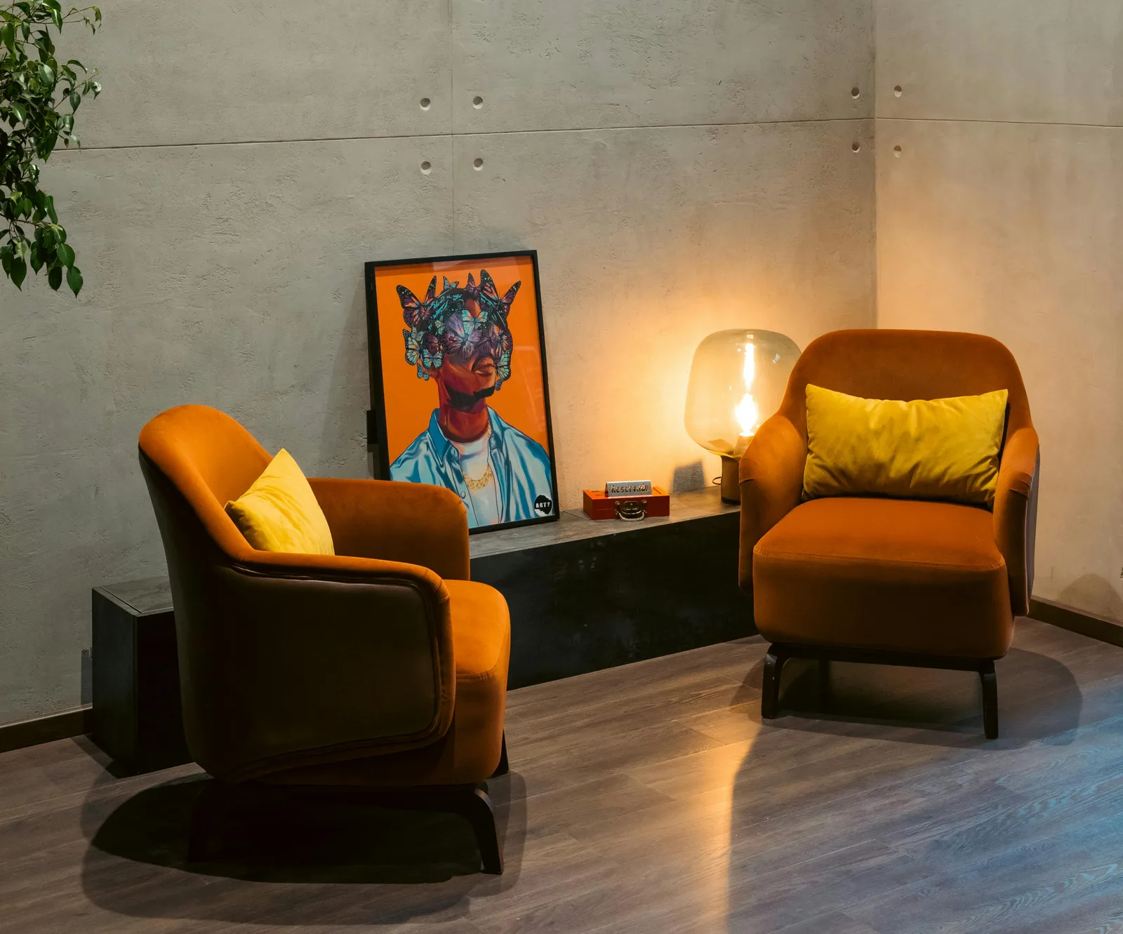 Two orange armchairs with warm lamplight and colorful wall art