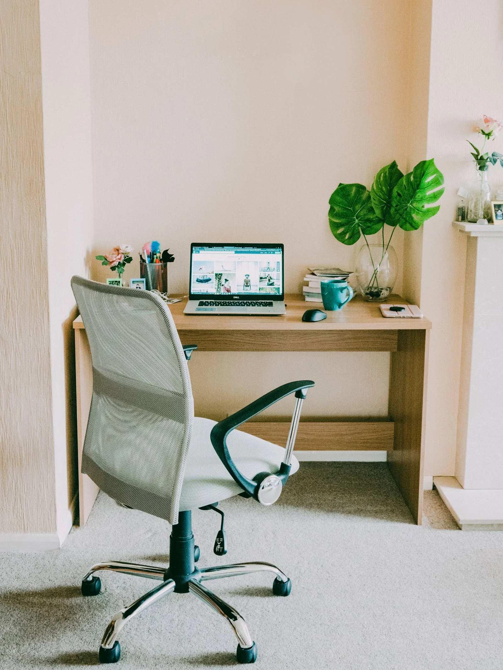 Compact wooden desk with a laptop and pale surrounding walls in daylight