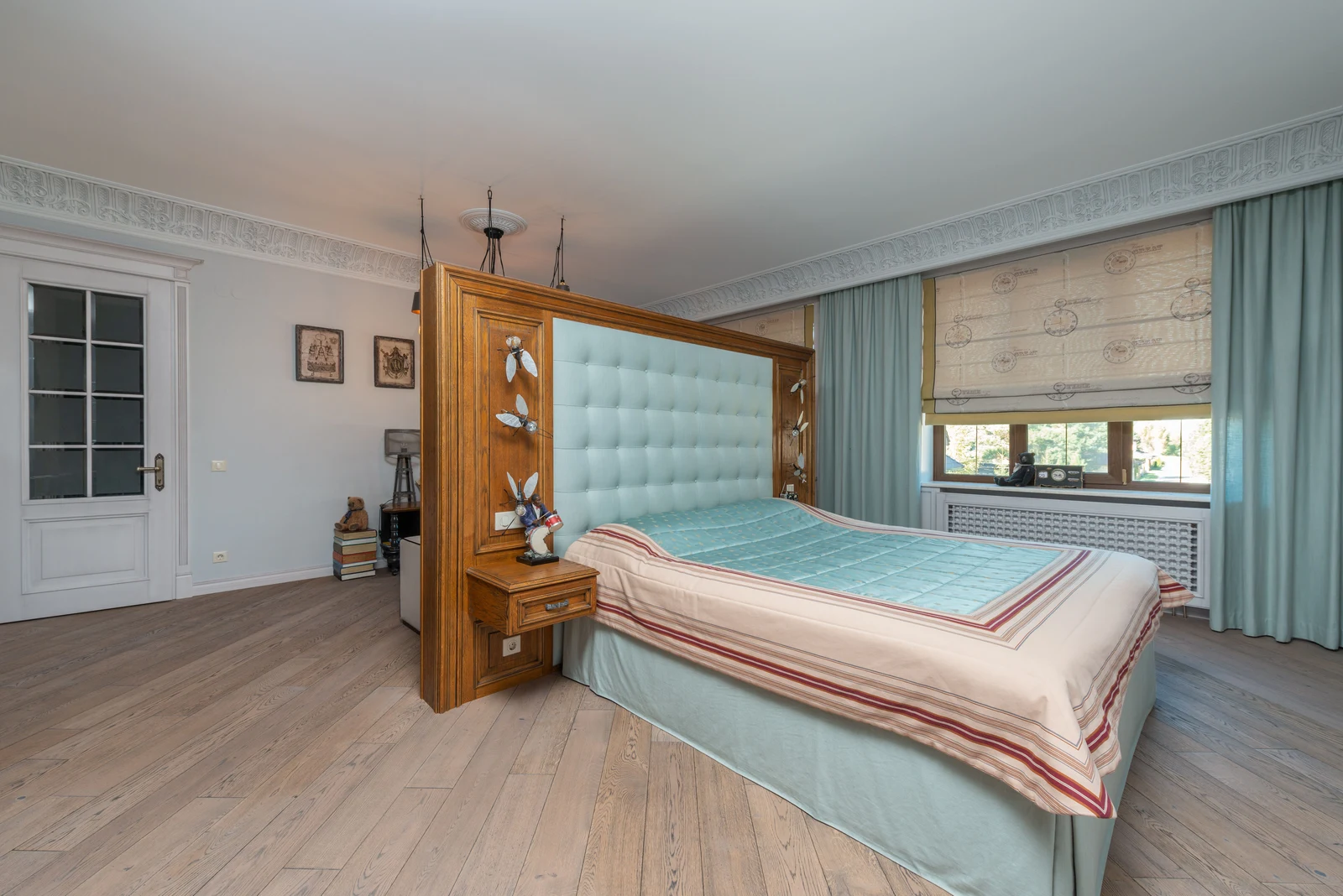 A bedroom with a substantial timber-framed headboard, a side doorway and a window