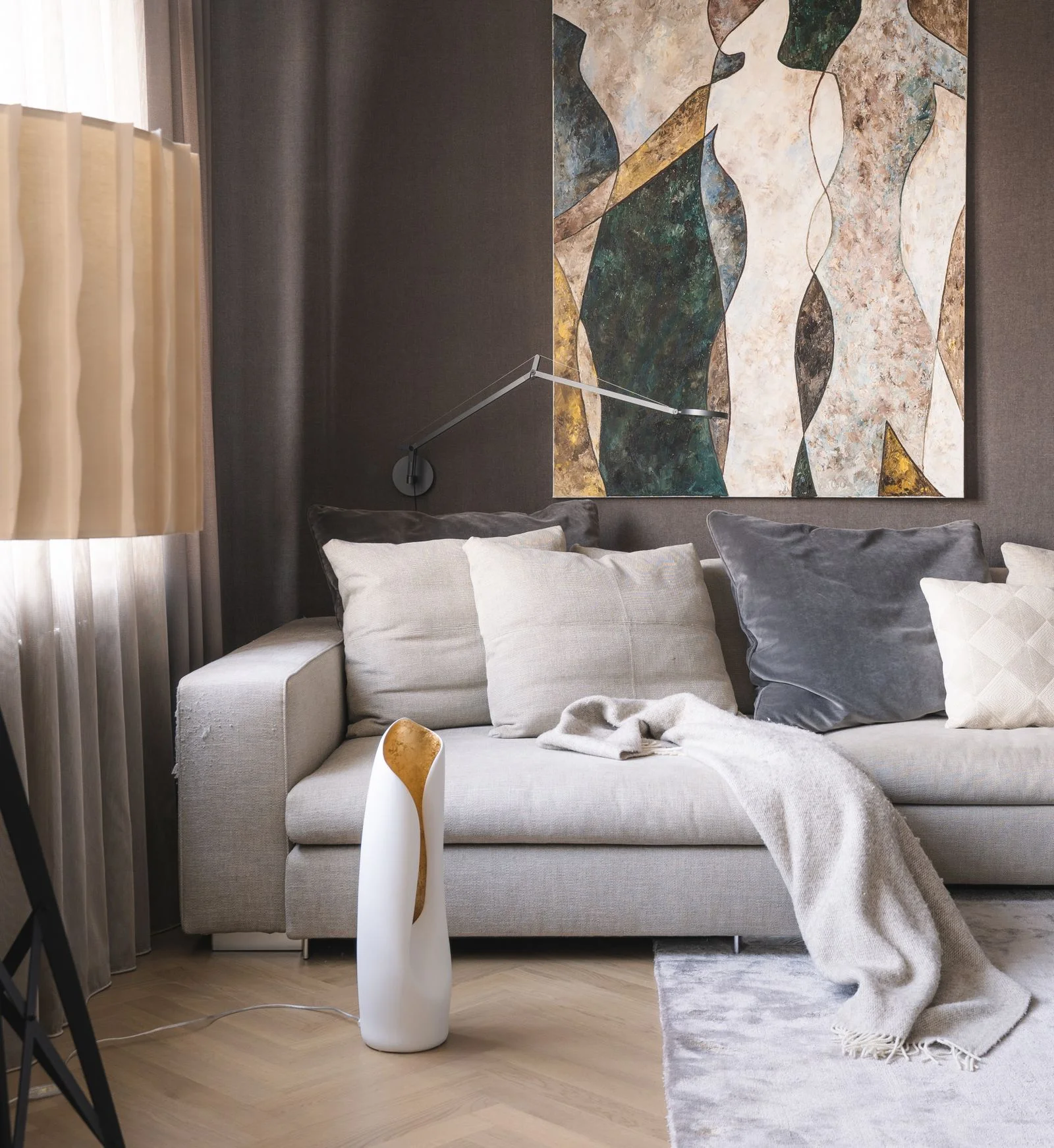 Large abstract canvas above a gray sofa, repeating cream, charcoal and muted green