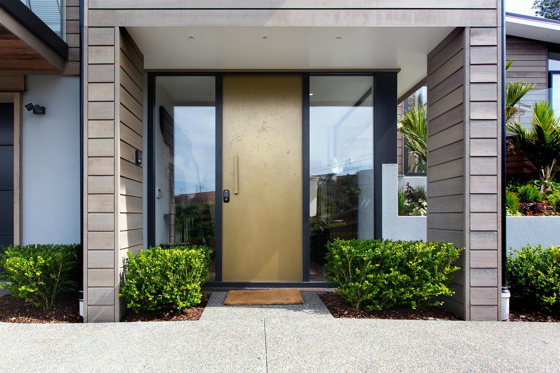 Modern home entrance with balanced landscaping and a centered front door