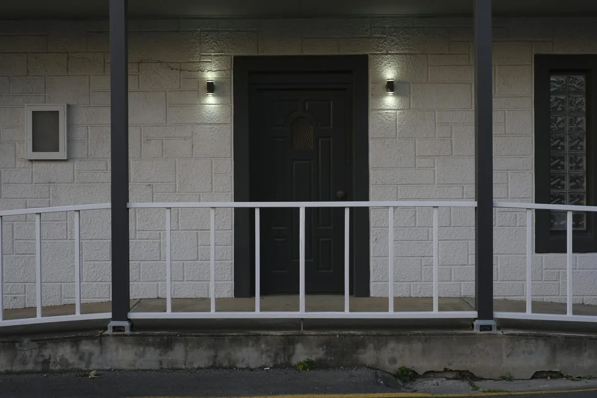 Dark charcoal front door centered on a white modern porch with black trim and exterior lights