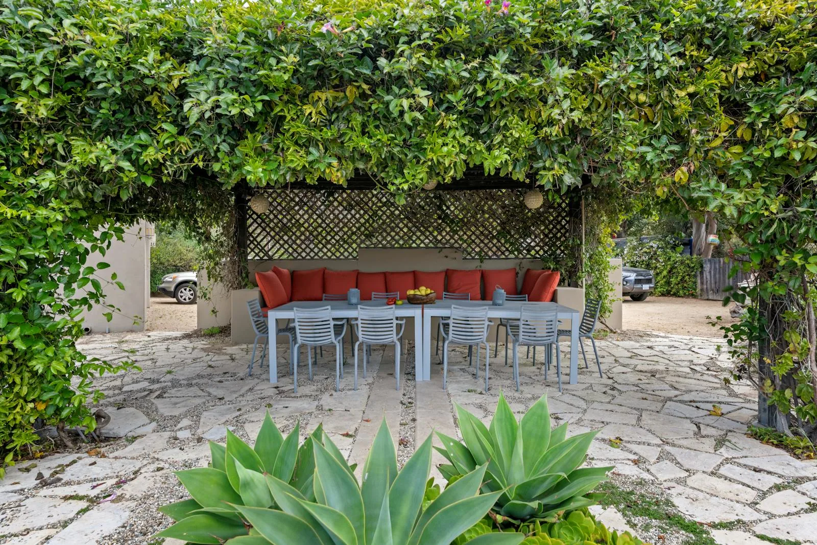 Brick patio and lawn outside a home with open doors and a simple outdoor setup