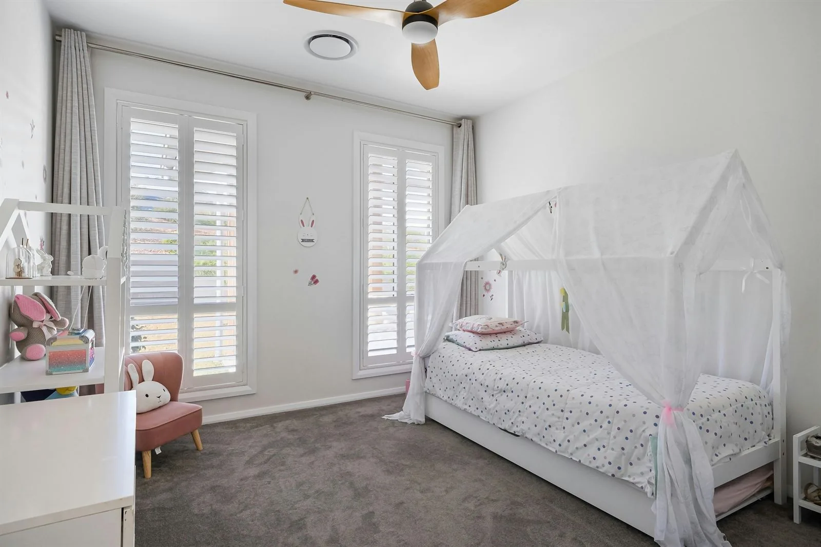 Kids room with canopy bed, desk, and clear open path through the middle of the room