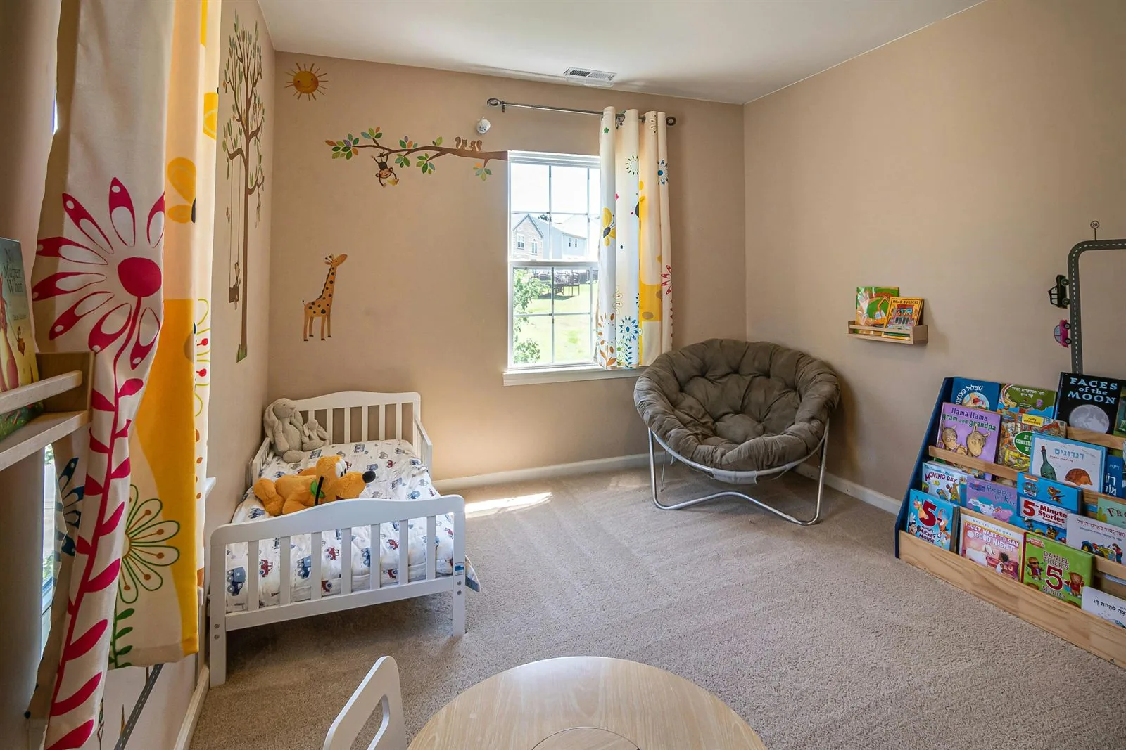 Toddler bedroom with low bed, front-facing book ledge, reading chair, and open floor area