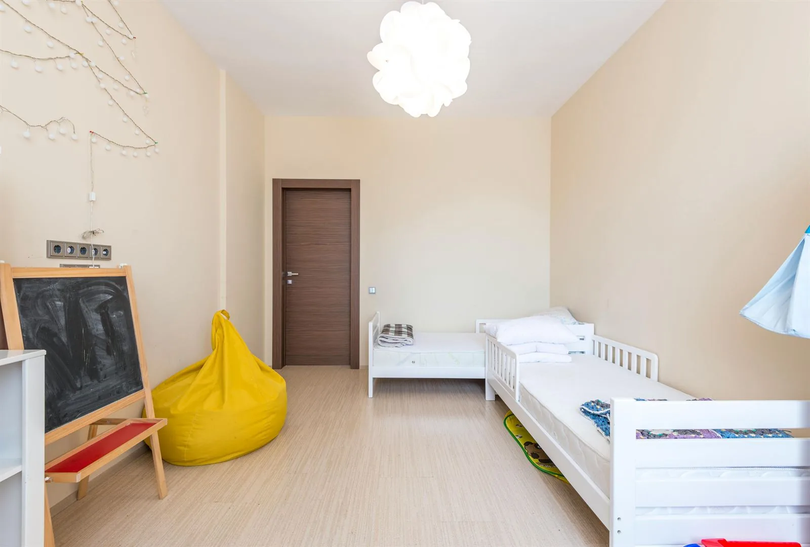 Kids bedroom with two low twin beds, beanbag chair, chalkboard, and wide open floor