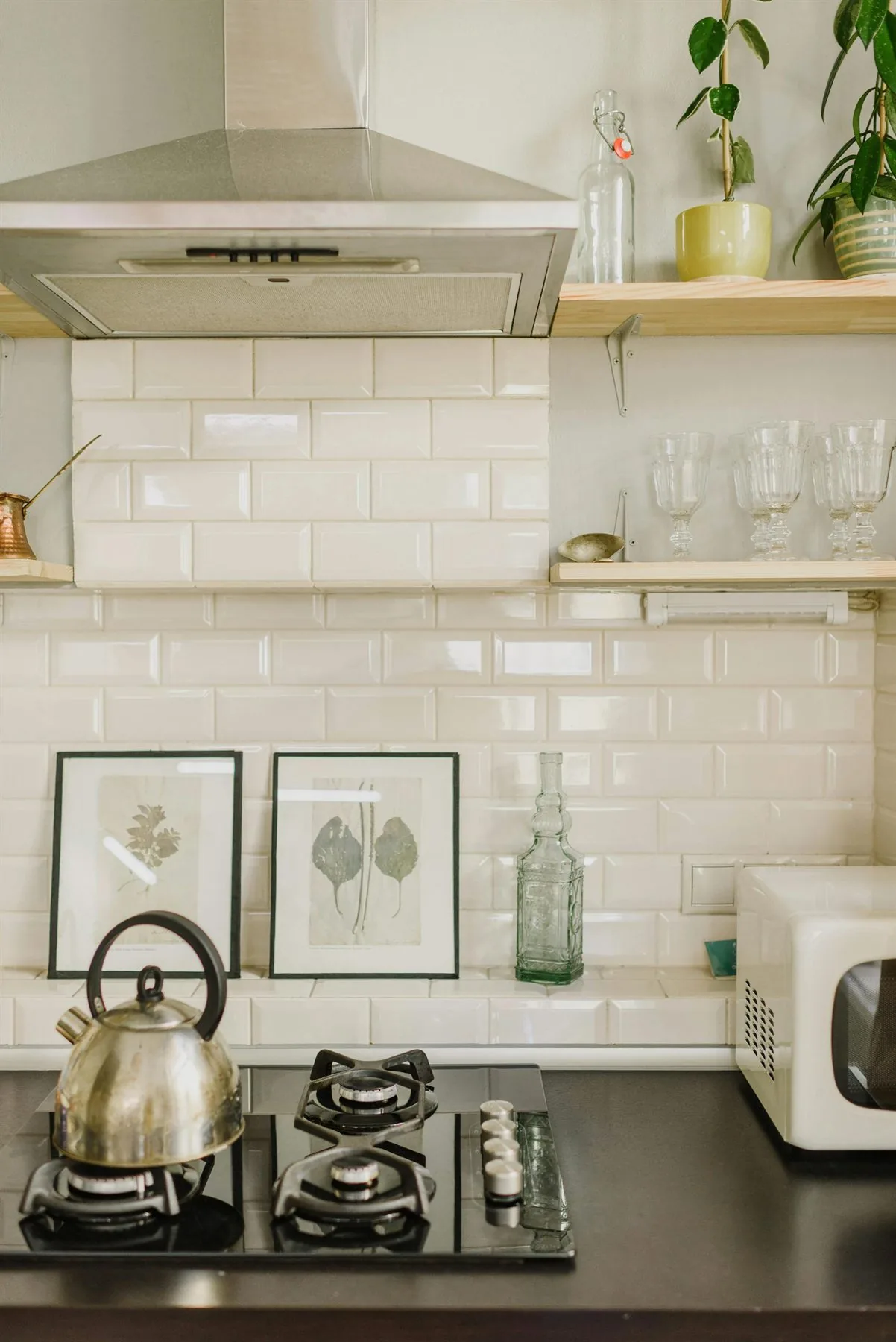 Clean kitchen corner with white tile, open shelves, and a tidy stovetop