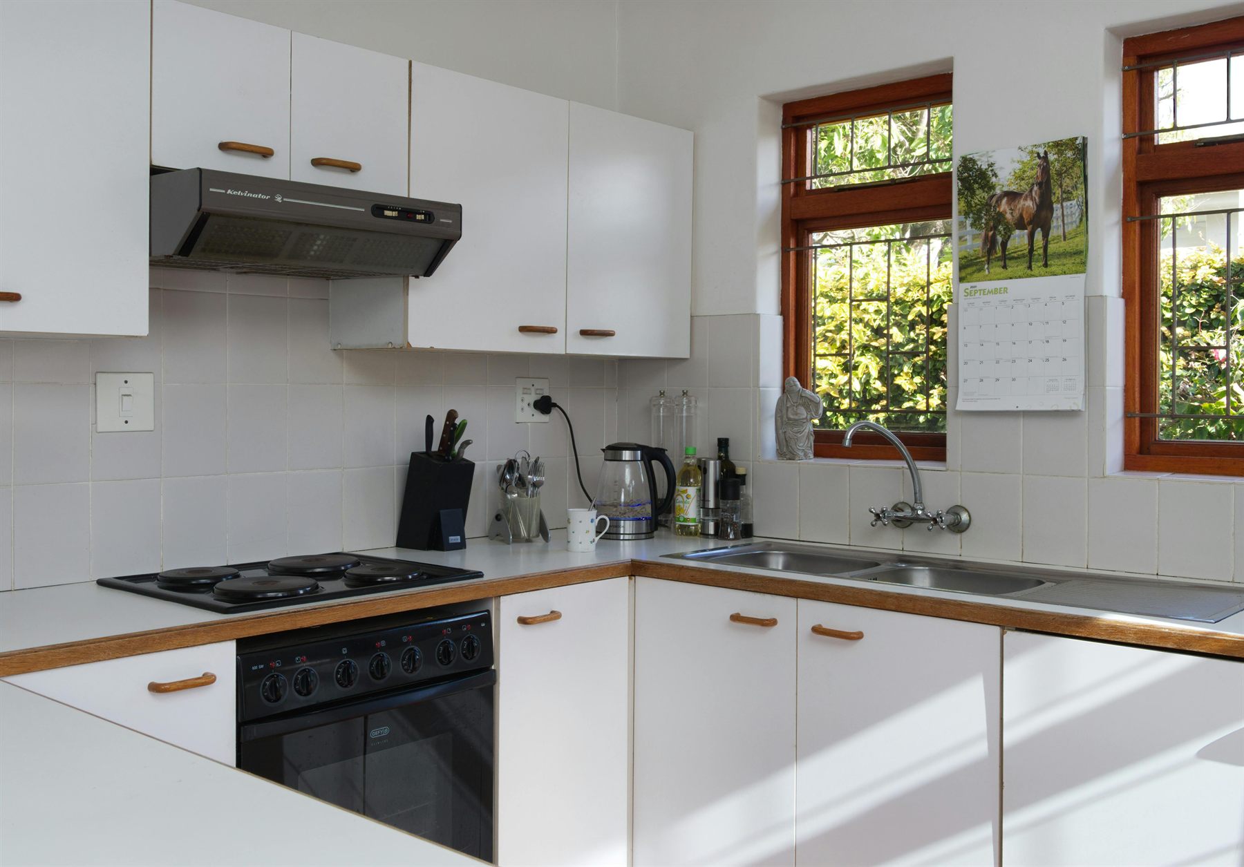 White kitchen with wood trim, sunny windows, and a bright clean palette