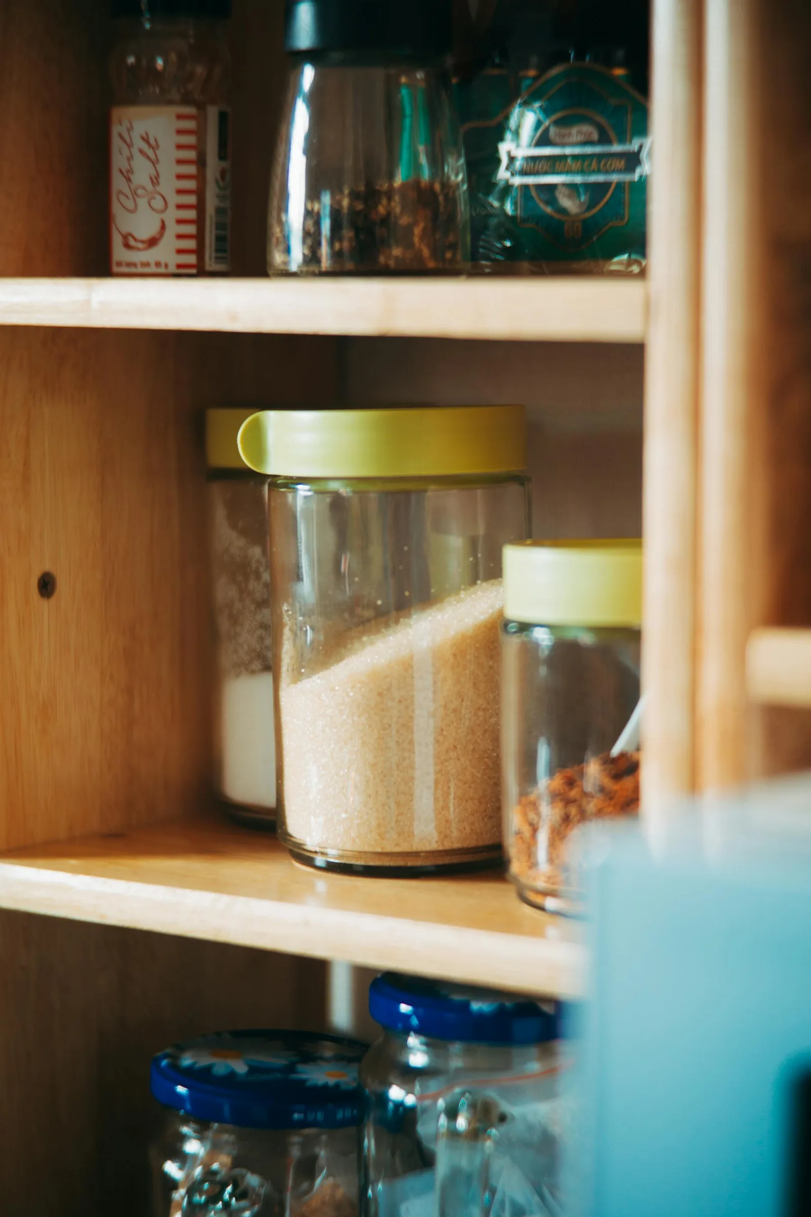 Kitchen shelf with glass jars, dry goods, and warm organized storage