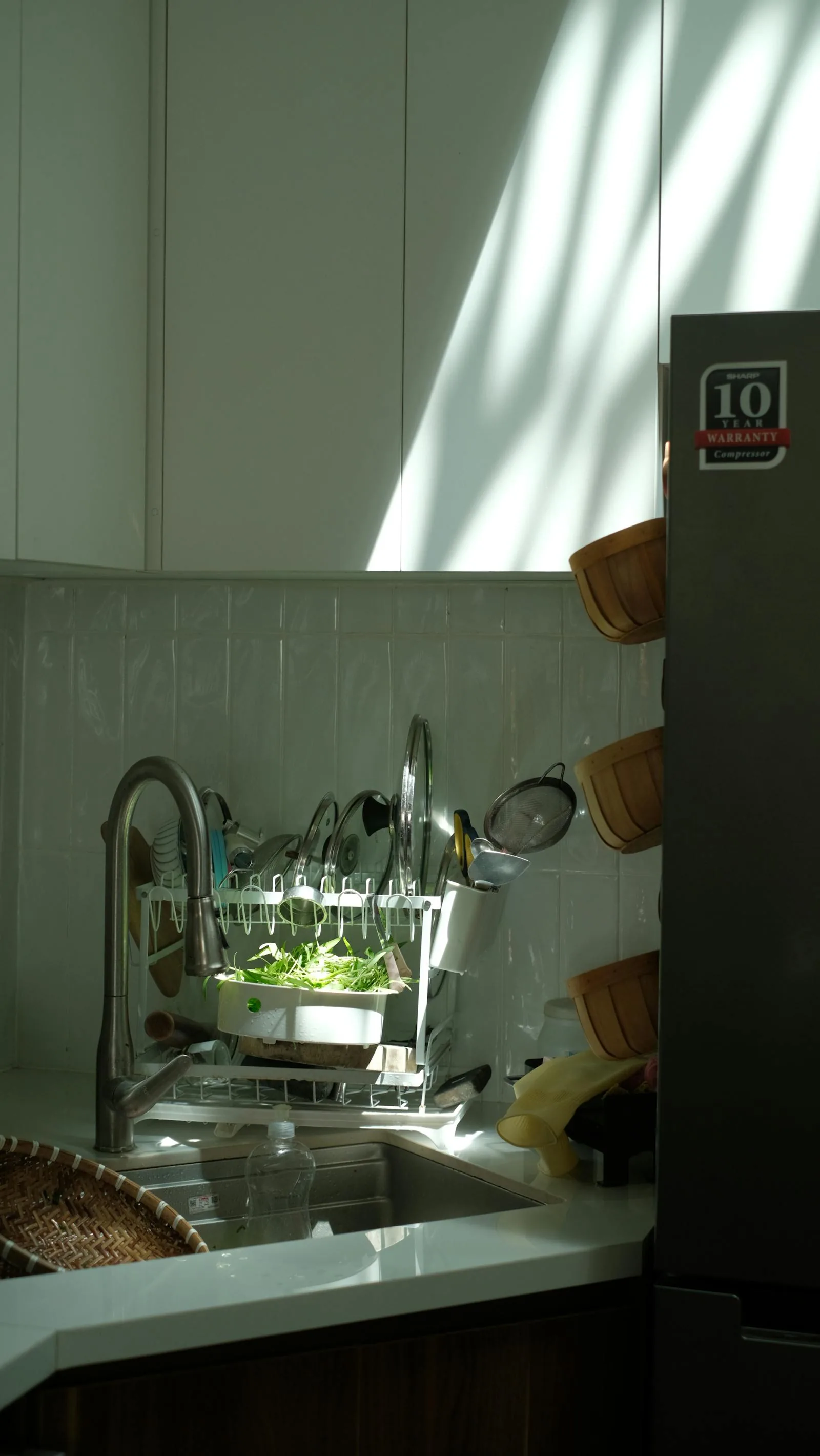 Small kitchen sink with soft daylight, pale cabinets, and a calmer working area