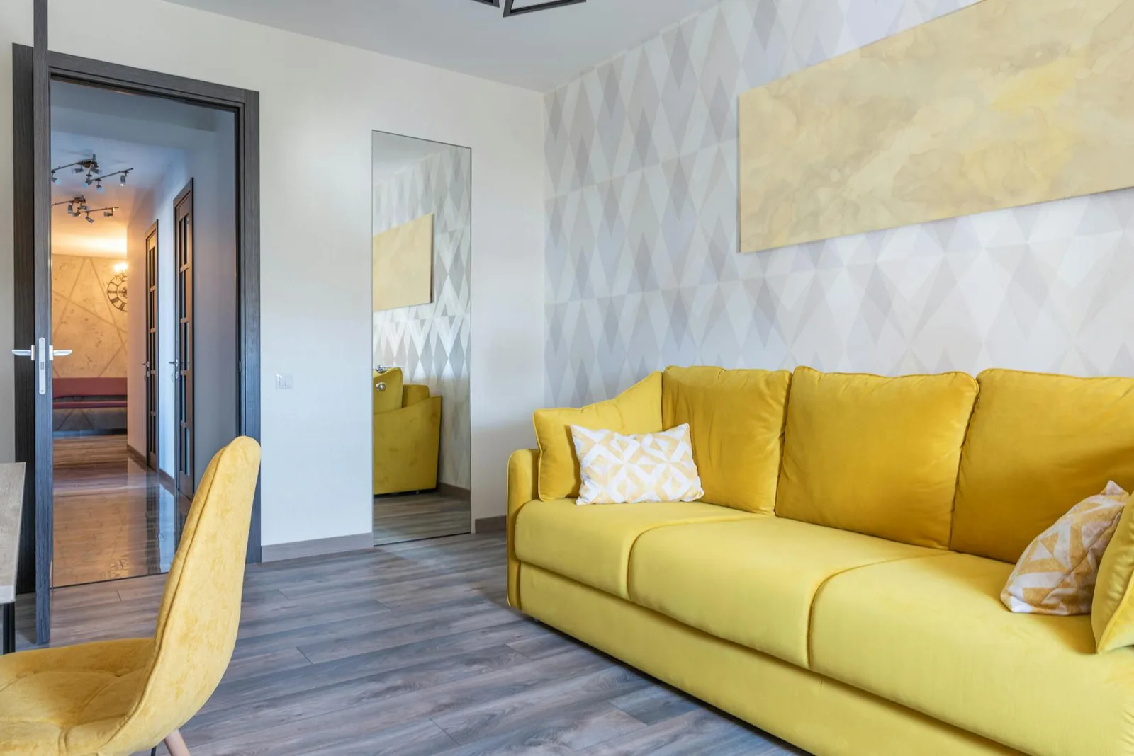 Living room with yellow sofa, mirror, strong pattern, and multiple attention points