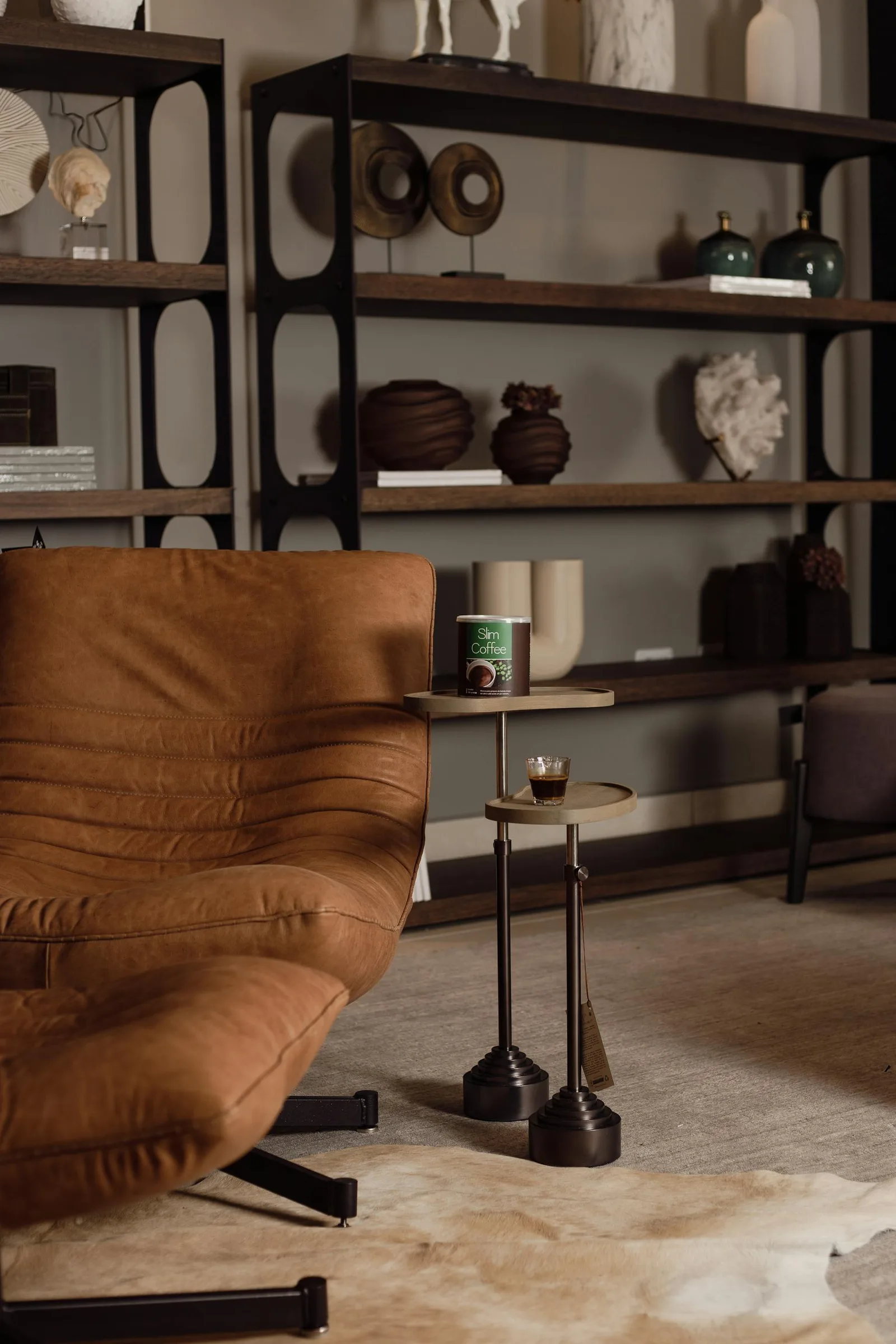 Living room with sofa, small table, open shelving, and many decorative objects behind the seating area