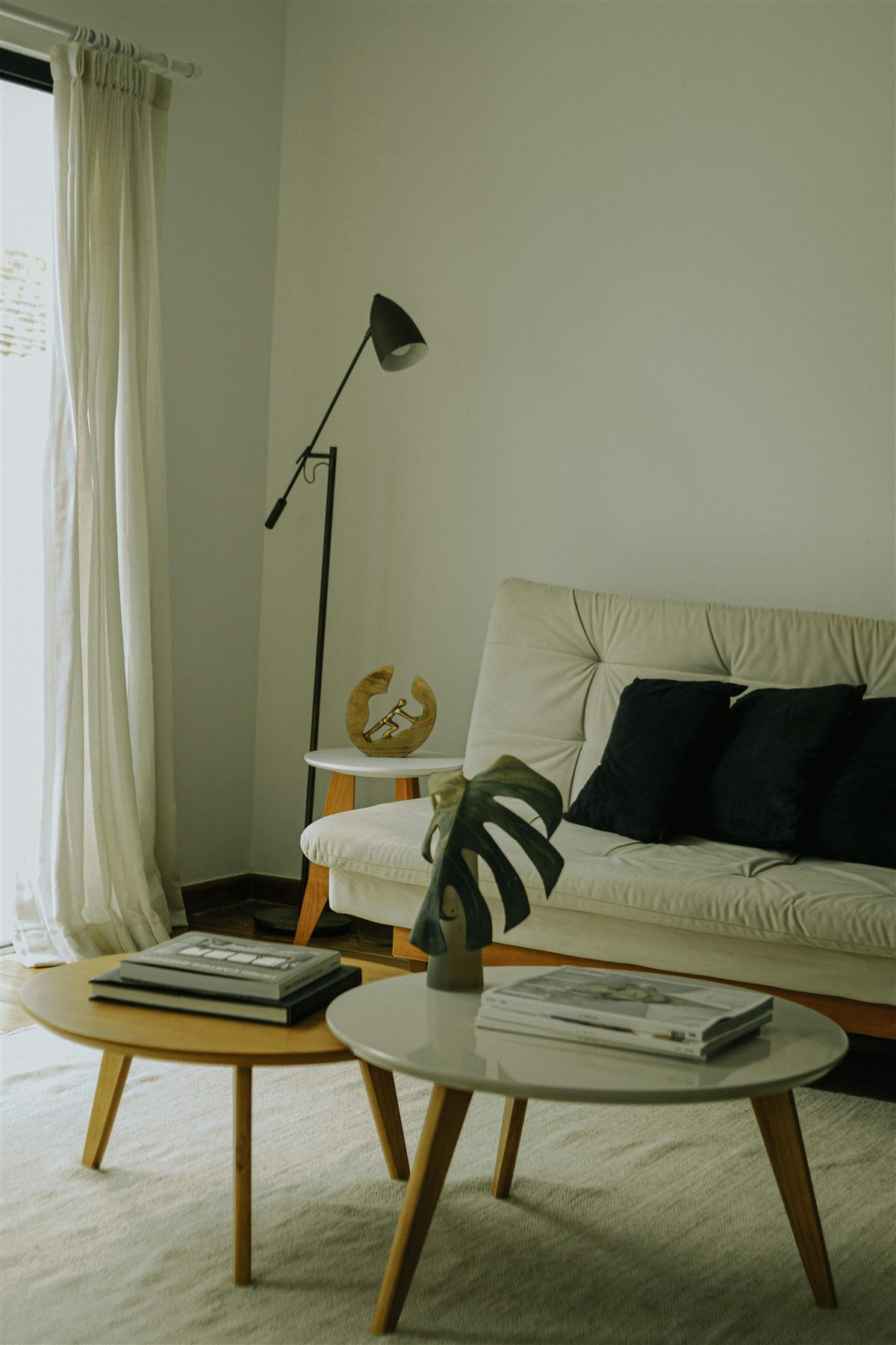 Soft neutral living room with ivory sofa, cream rug, black floor lamp, and light wood tables