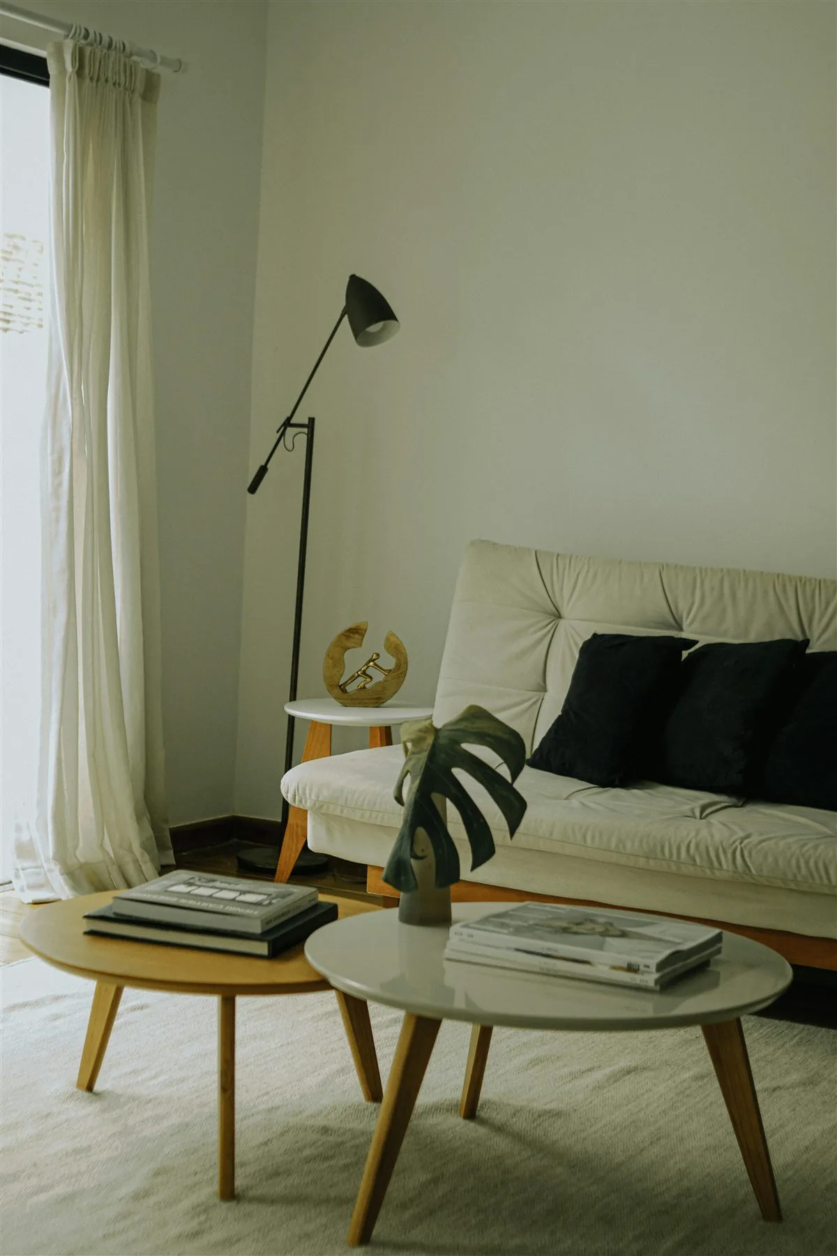 Soft neutral living room with ivory sofa, cream rug, black floor lamp, and light wood tables