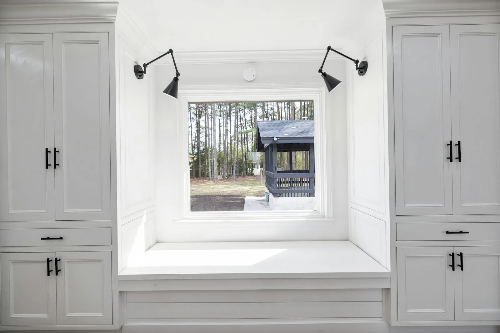 Mostly white office nook with black lamps, black chair, and stark contrast