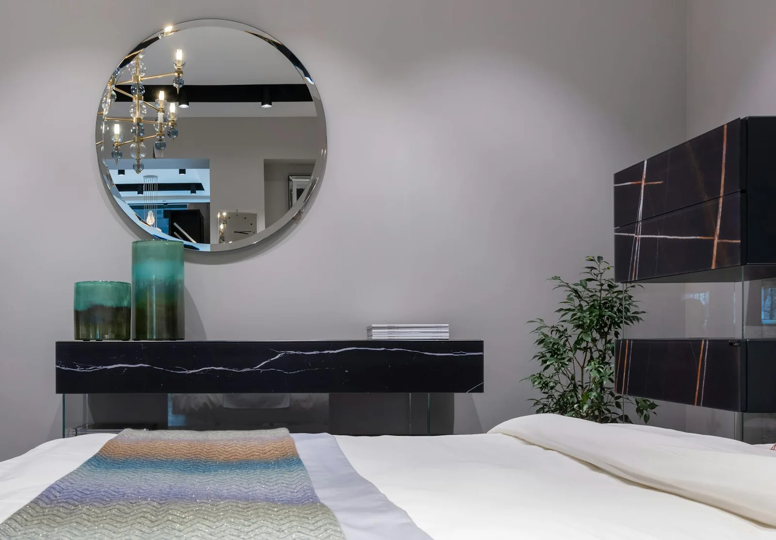 Bedroom with a round wall mirror placed away from the direct bed line