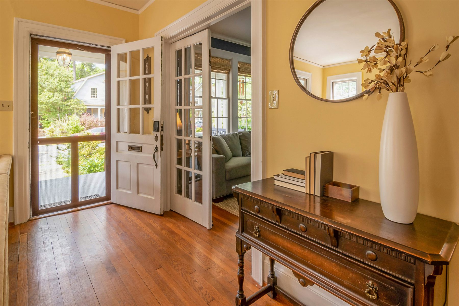 Warm yellow entry or dresser corner with a round mirror and a wooden table