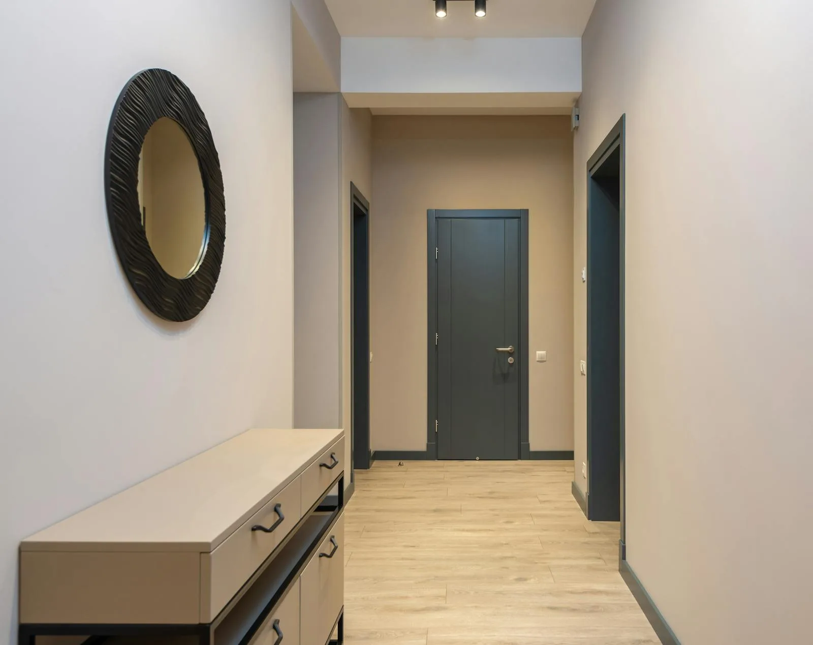 Minimal hallway with a round wall mirror and a long console beneath it