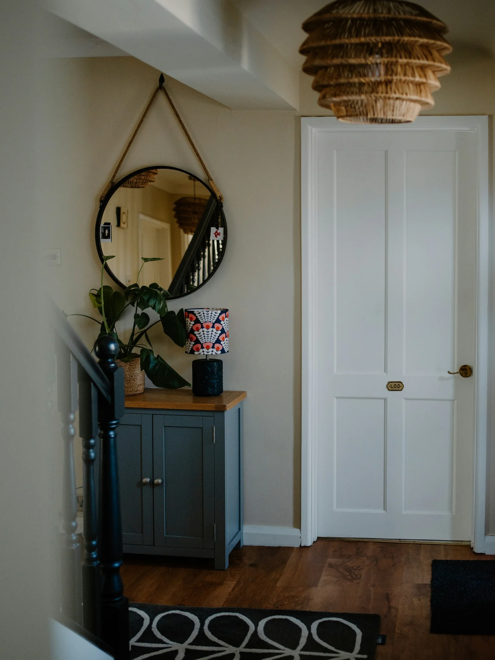 Round hallway mirror above a small cabinet near a closed interior door