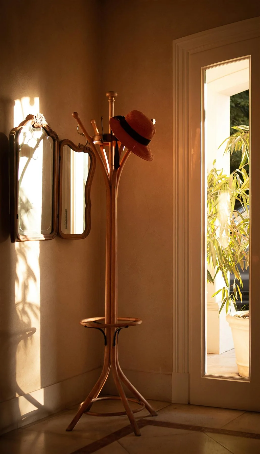 Sunlit narrow entry with a small wall mirror and lighter uncluttered styling