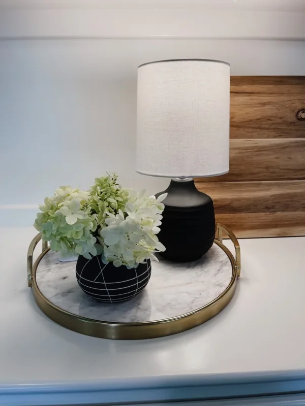 Round tray with a lamp and flowers arranged in a calm edited grouping