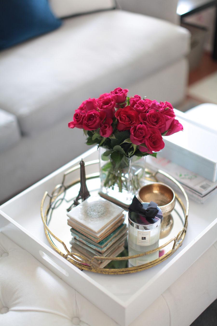 White coffee table with a round tray, pink roses, and a few carefully grouped objects