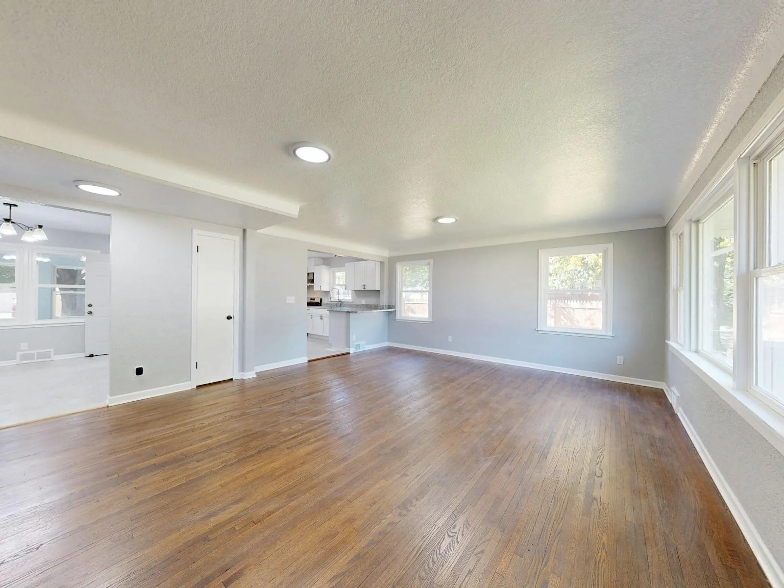 Open empty living room with wood floors, daylight, and enough space to understand the layout before decorating