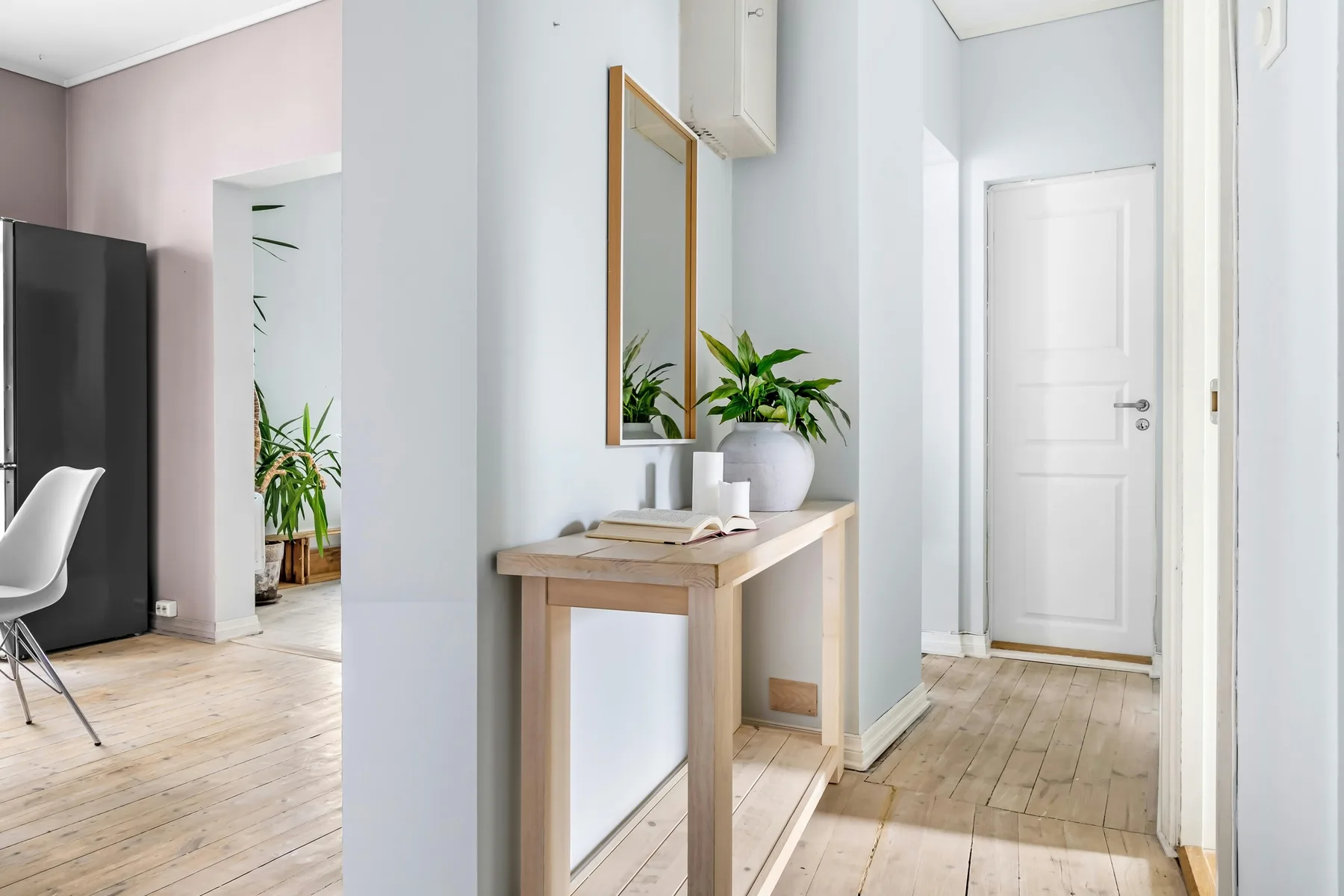 Softly styled entry console with mirror, plant, and a calm welcoming hallway