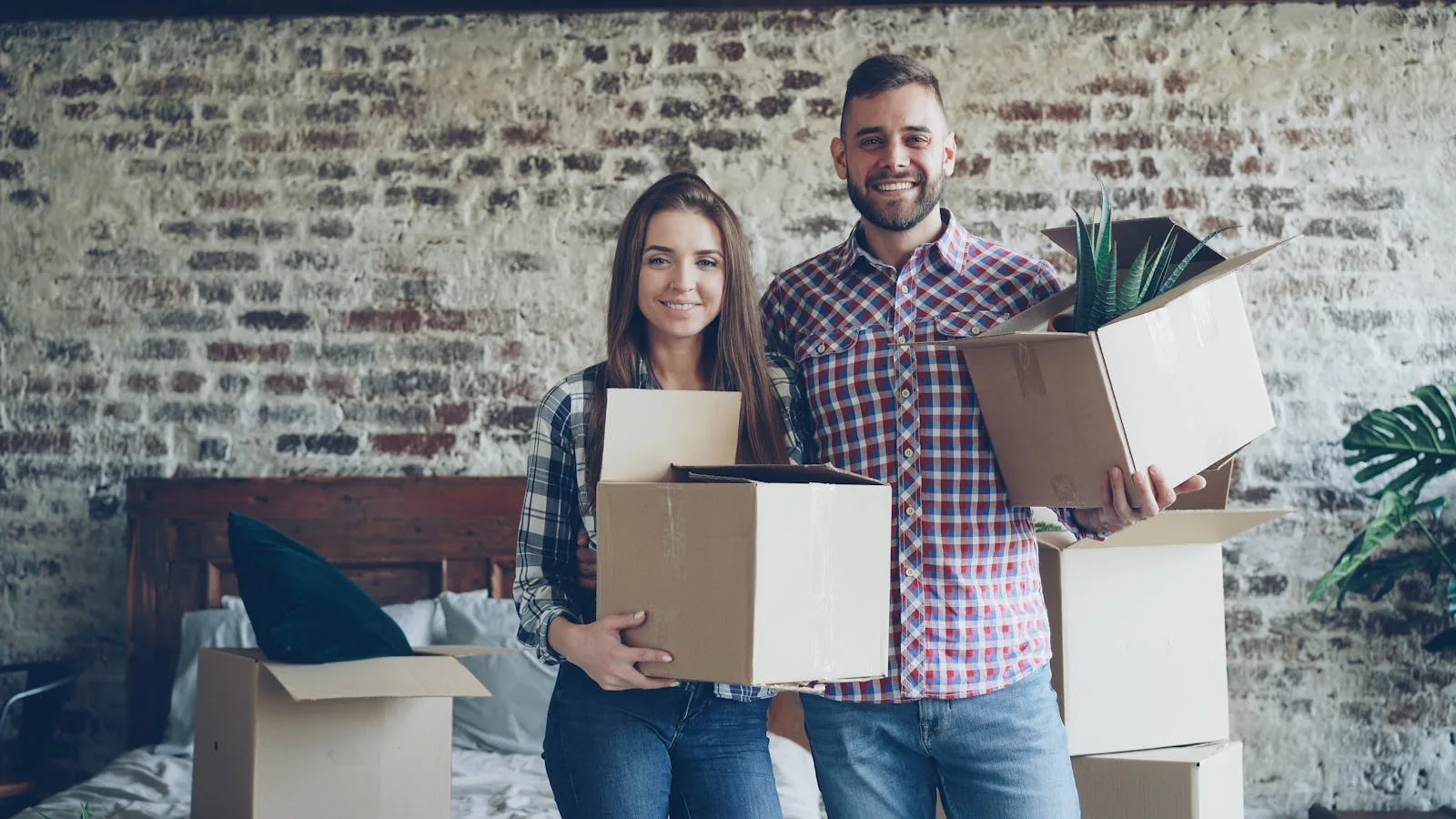 Couple carrying moving boxes into a new home while unpacking and settling in