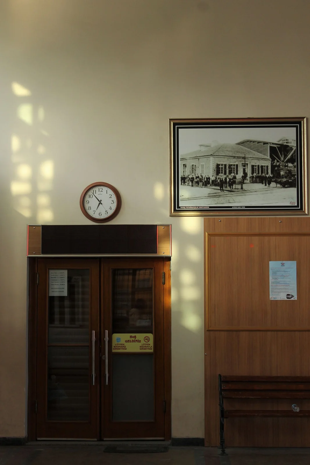 Wall clock above a timber doorway beside framed artwork
